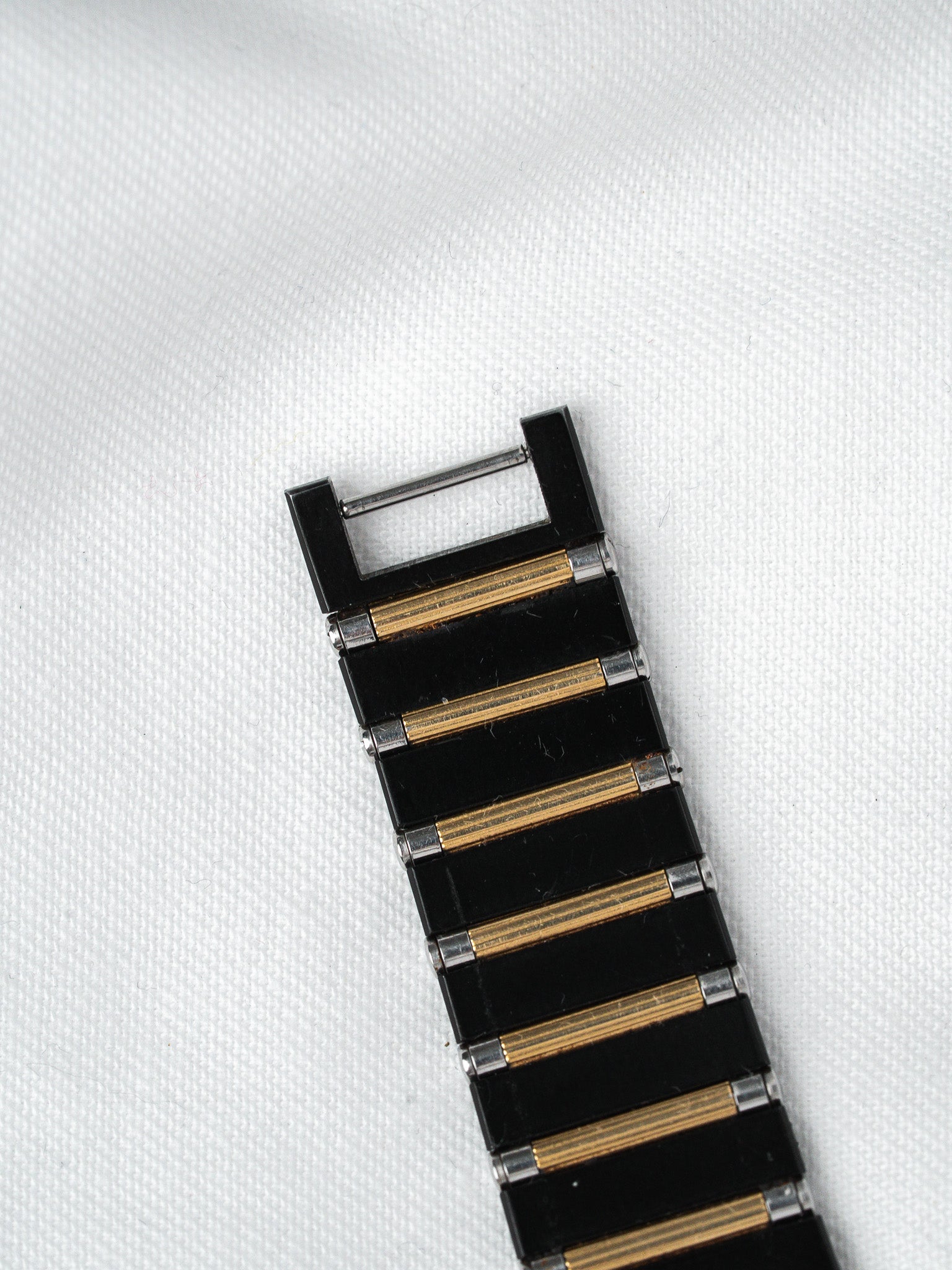 Vintage watch bracelet with black enamel and gold accents on white background