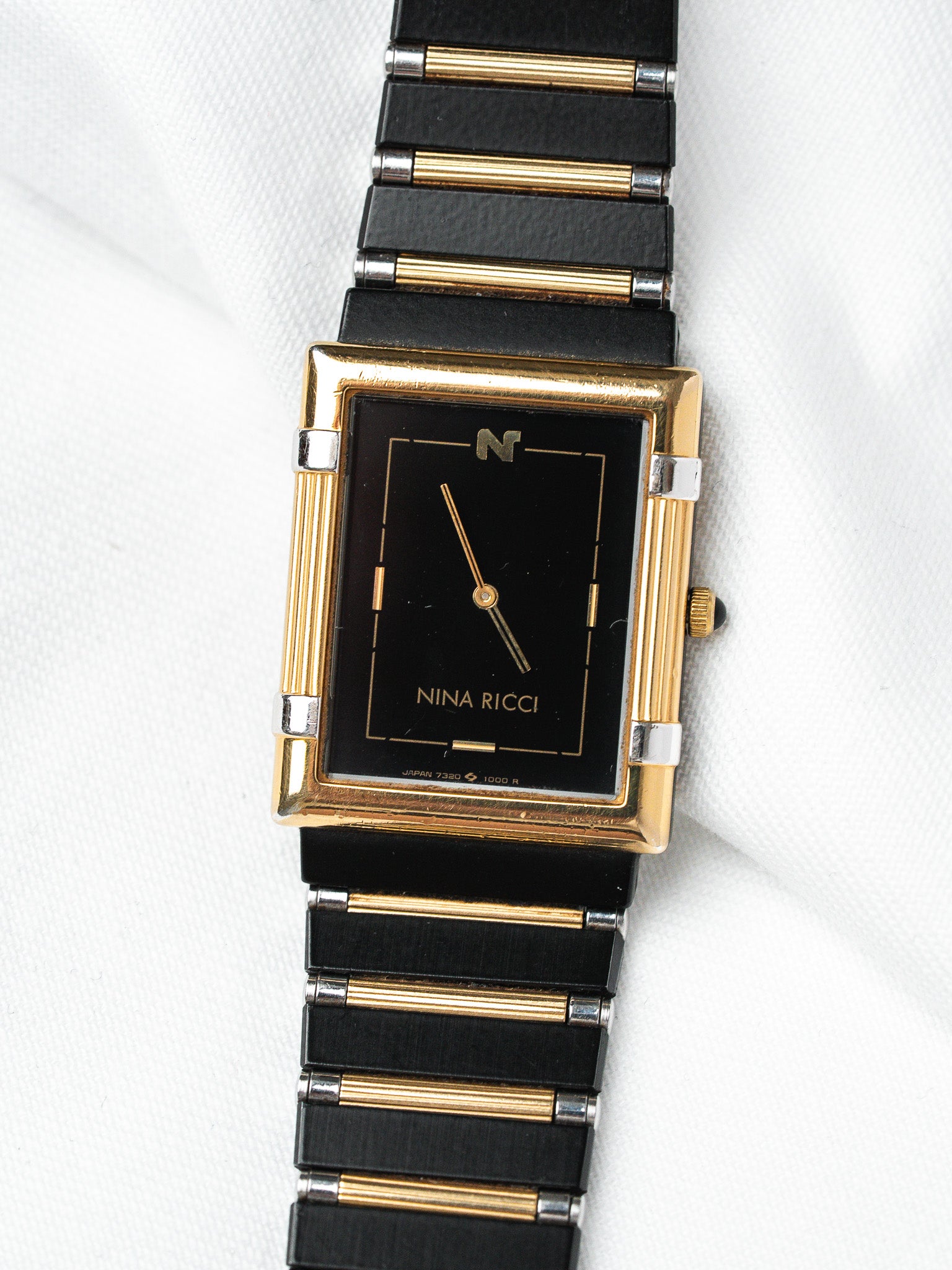Nina Ricci vintage watch with black dial, gold accents, and black bracelet