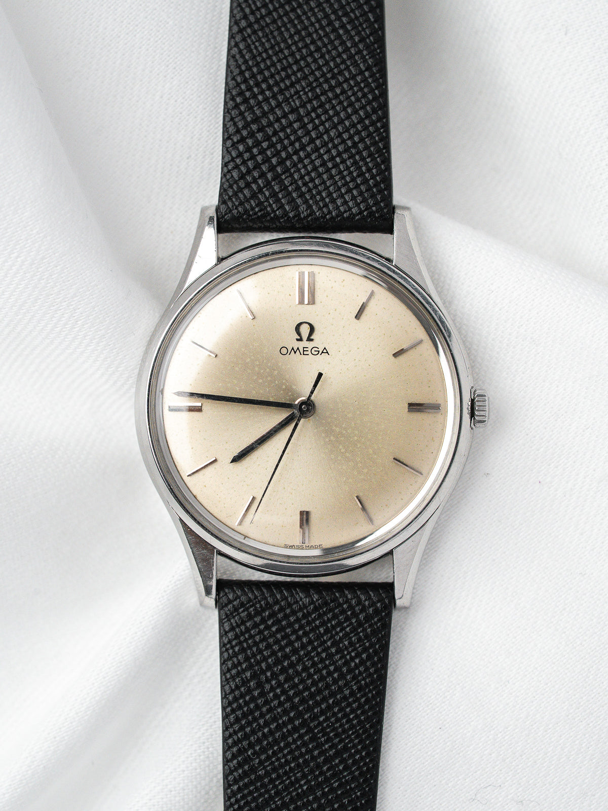 Omega vintage watch with cream dial, black strap, and stainless steel case