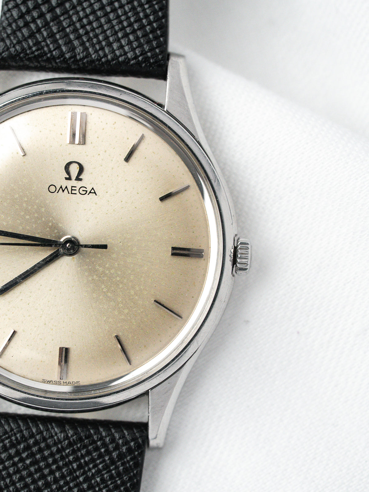 Vintage Omega watch with cream dial, black leather strap, and steel case