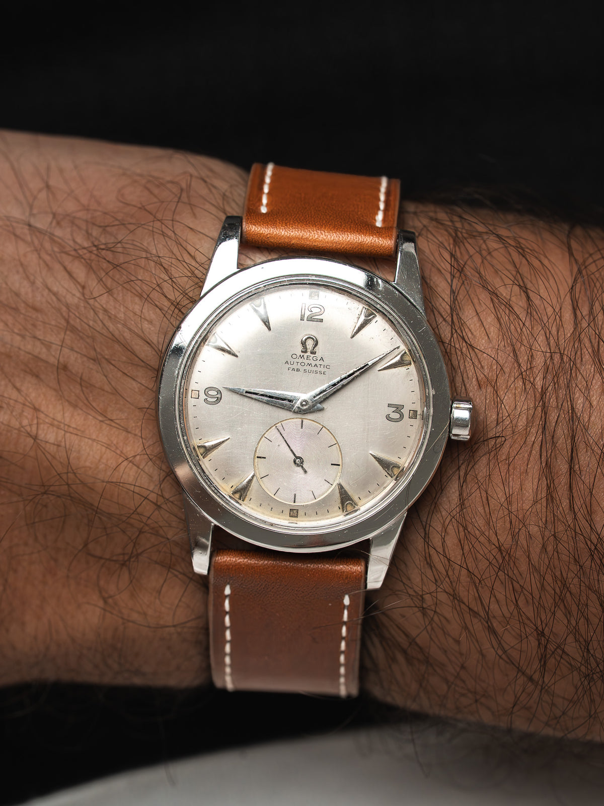 Montre Omega vintage automatique, cadran argenté et bracelet en cuir marron, portée au poignet