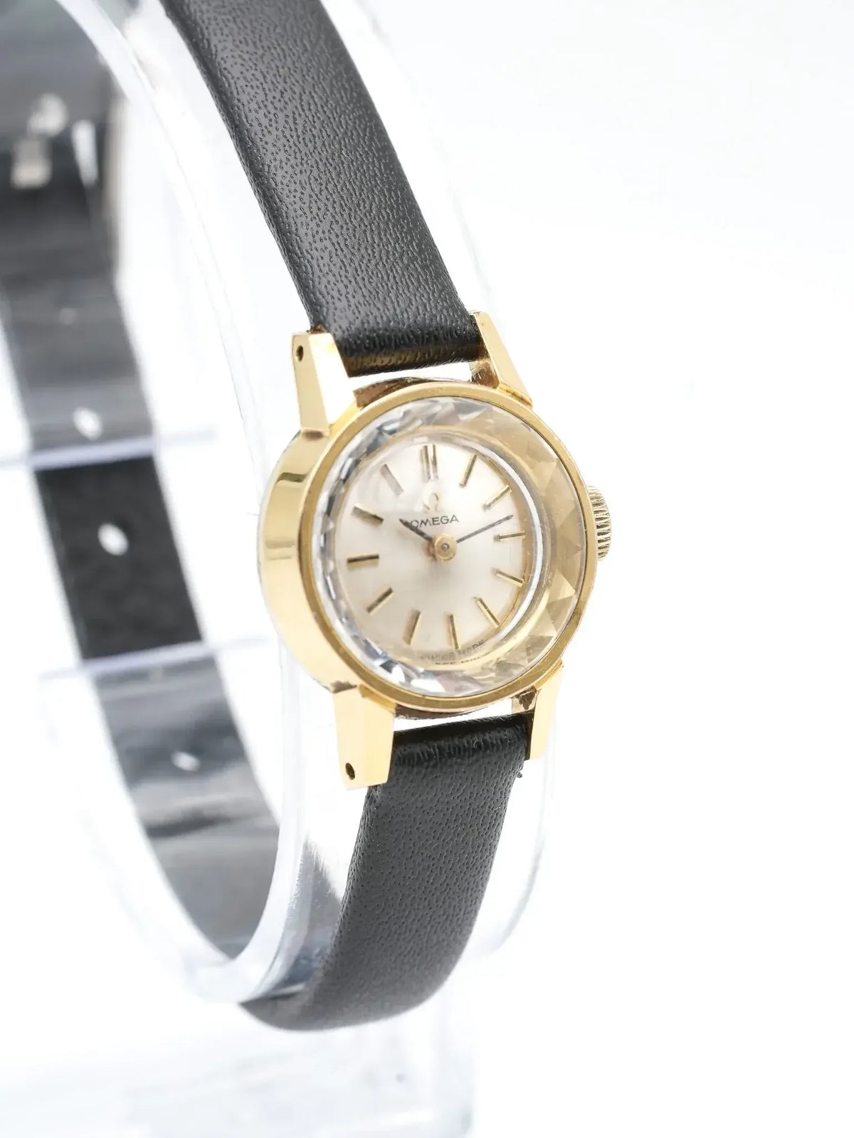 Vintage Omega watch with gold case, cream dial, black leather strap on display stand