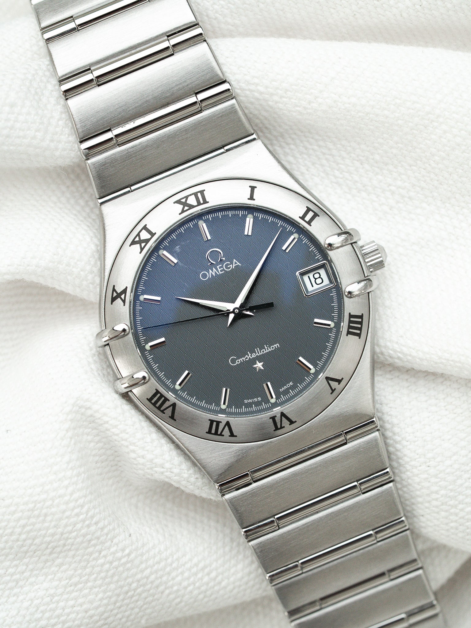 Omega Constellation vintage watch with blue dial, Roman numerals, steel bracelet on white fabric