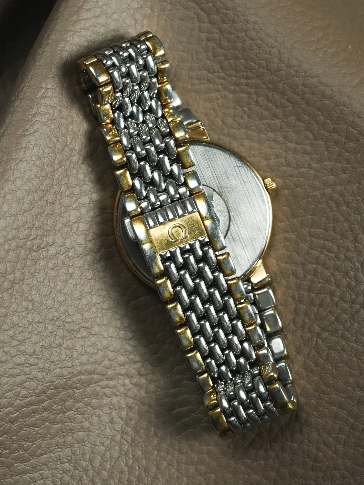 Omega vintage watch with two-tone bracelet, gold accents, on textured leather