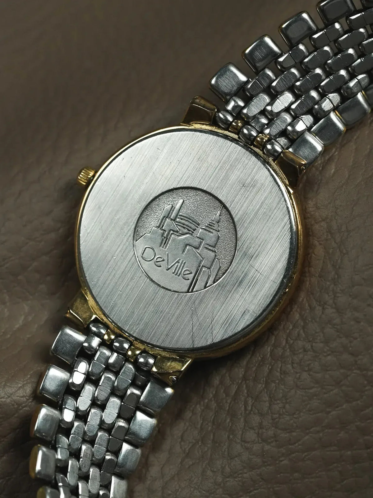 DeVille vintage watch back with engraved logo, two-tone bracelet on textured surface