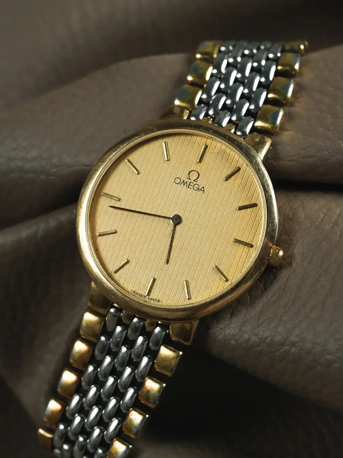 Omega vintage watch with gold dial and two-tone bracelet on wrist
