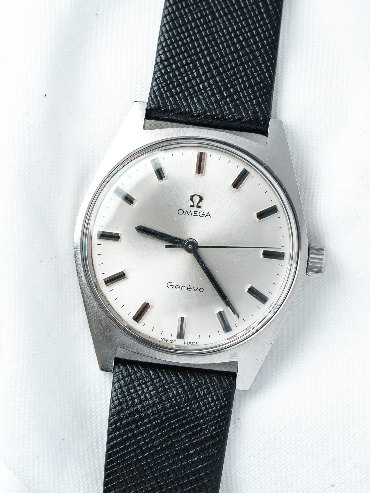 Omega Genève vintage watch with silver dial, black indices, and textured black strap