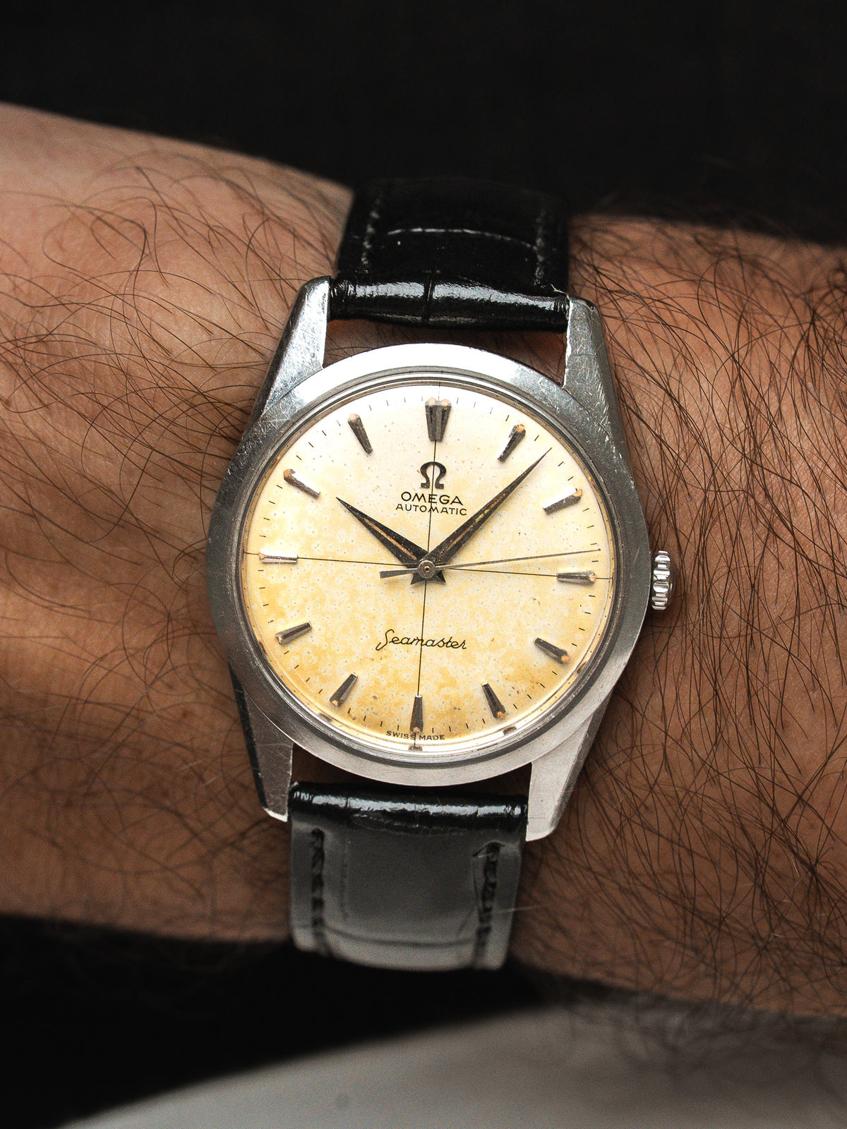 Montre Omega Seamaster vintage en acier, cadran crème patiné, bracelet cuir noir au poignet