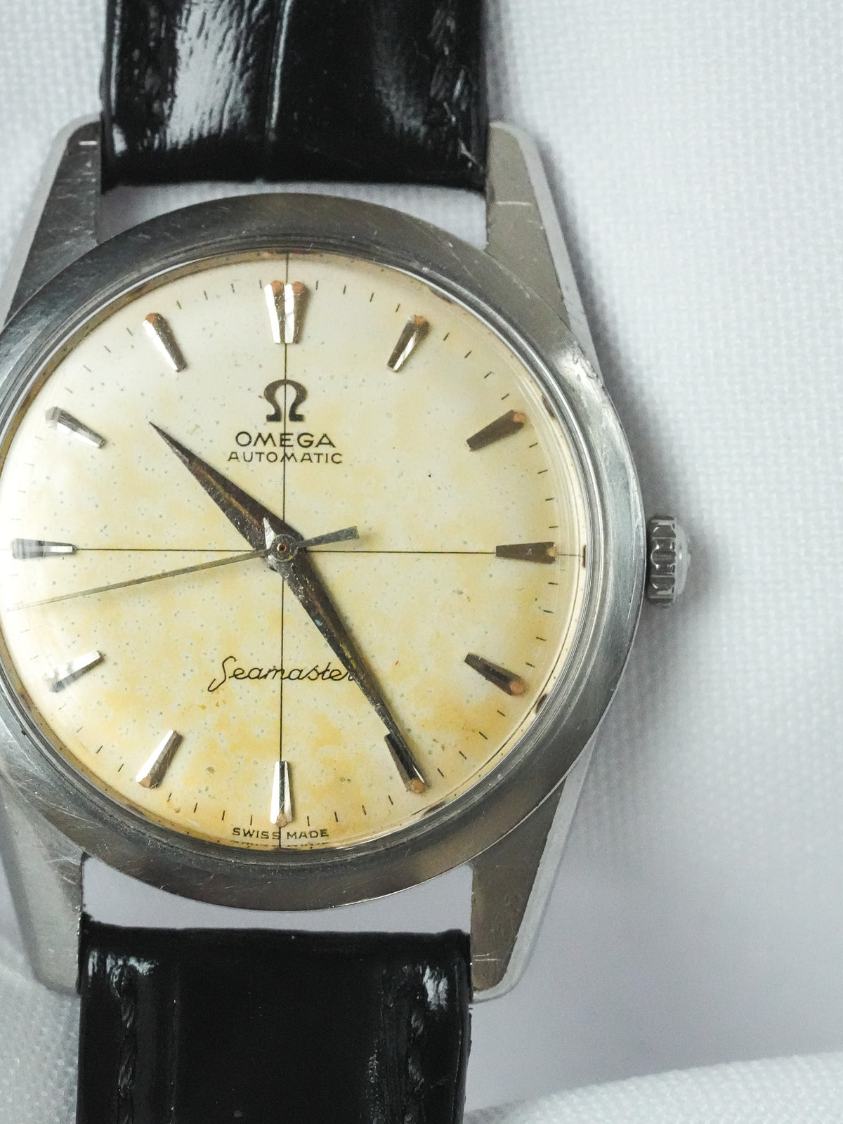Vintage Omega Seamaster automatic watch with cream dial, steel case, black leather strap on white background