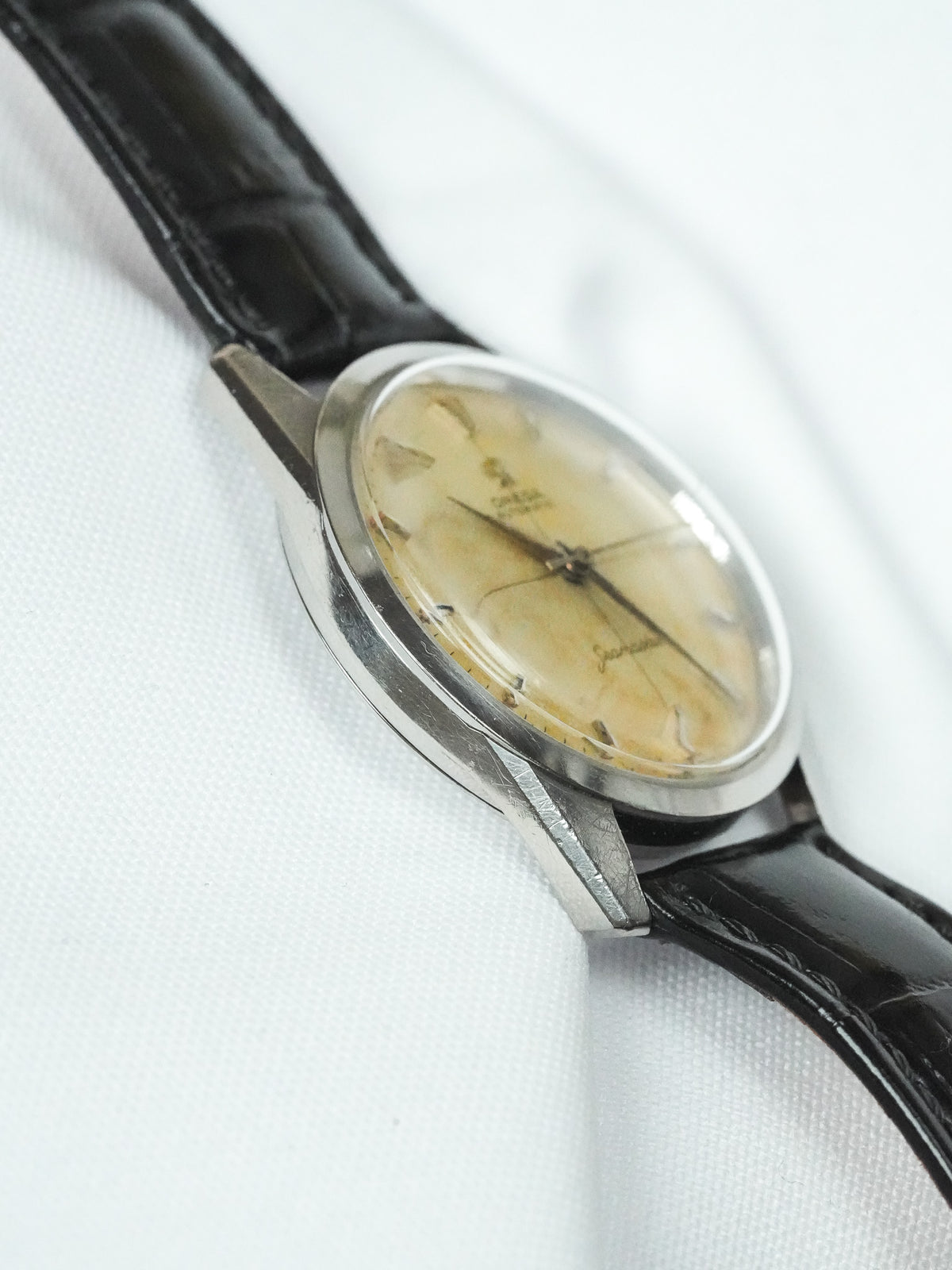 Vintage Omega watch with cream dial, black leather strap, and steel case