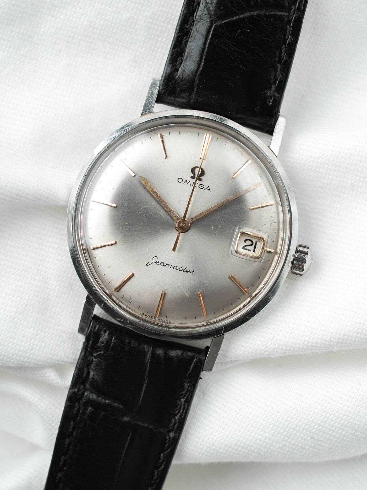 Montre Omega Seamaster vintage, cadran argenté et bracelet en cuir noir, fond blanc