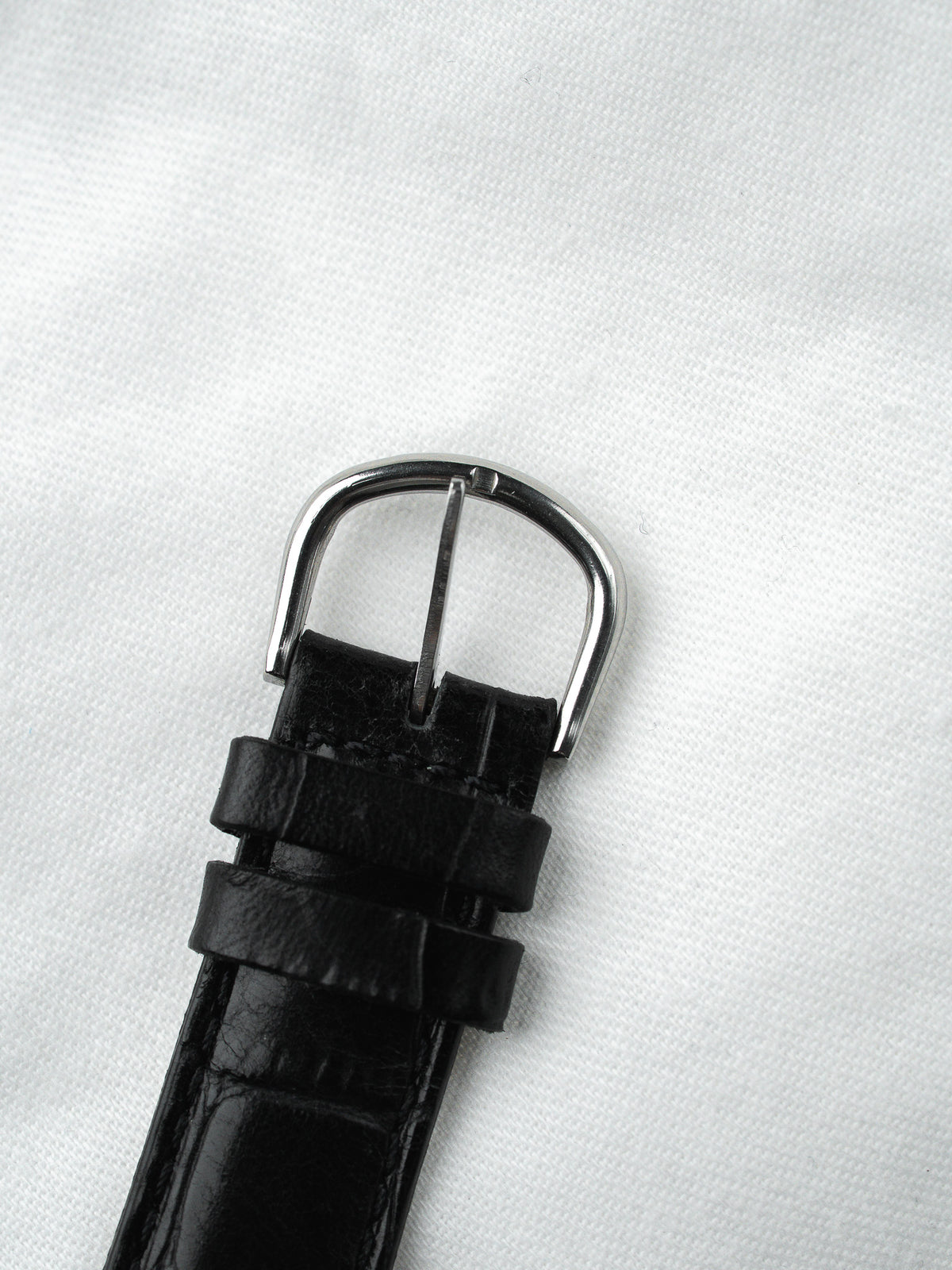 Boucle de bracelet de montre en cuir noir avec ardillon argenté sur fond blanc