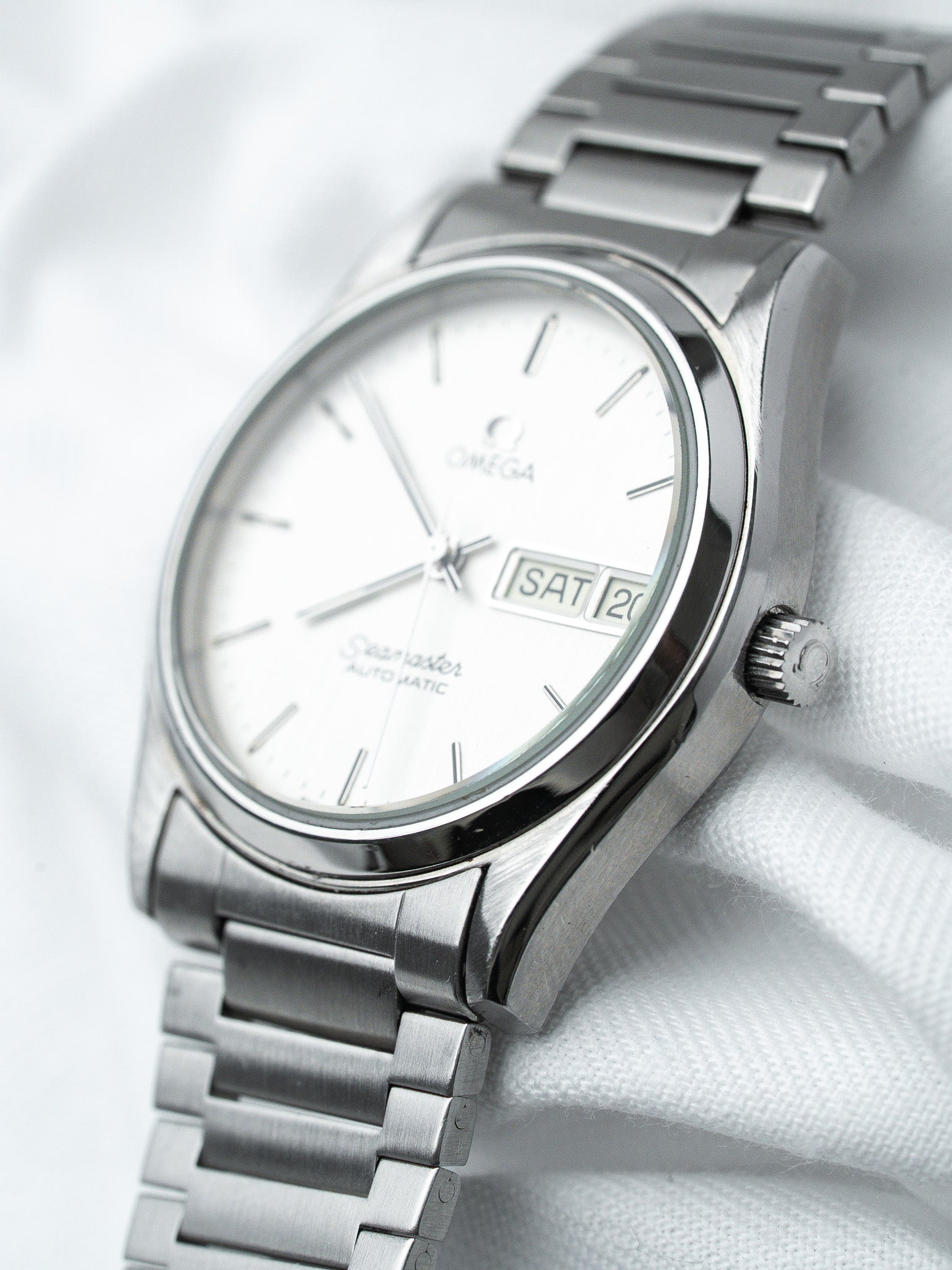 Omega Seamaster vintage automatic watch with white dial and steel bracelet on white fabric