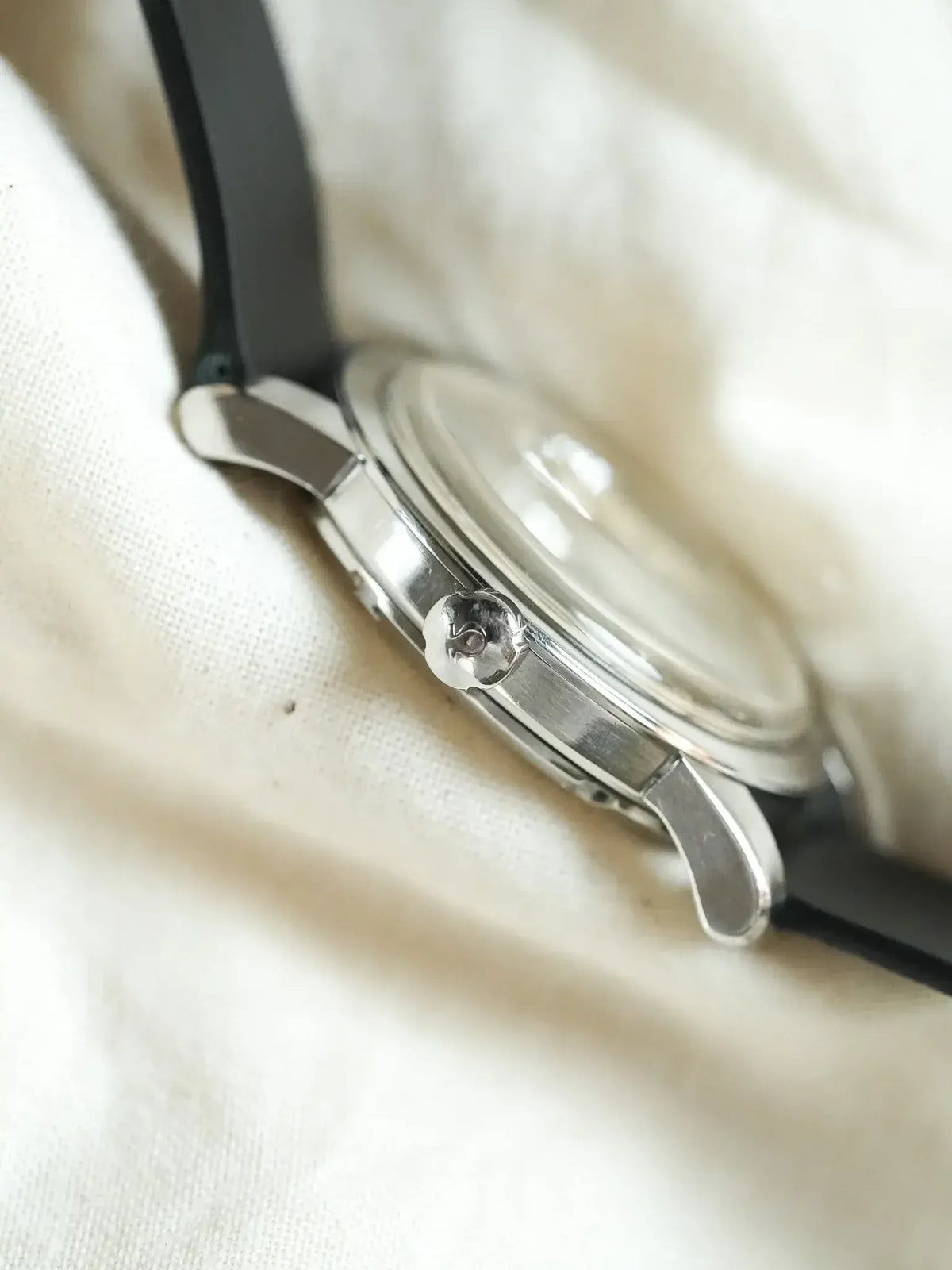 Vintage Omega watch with stainless steel case and black strap on fabric
