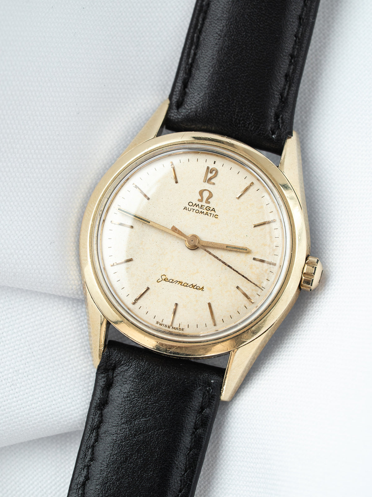 Omega Seamaster vintage watch with gold case, cream dial, and black leather strap