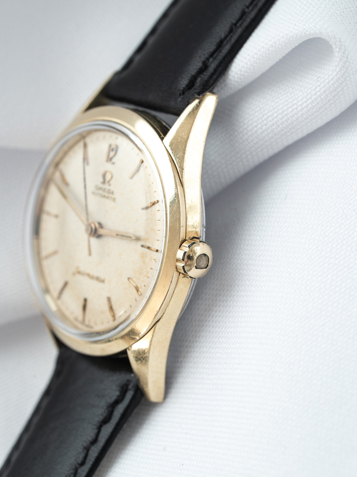 Vintage Omega watch with gold case, cream dial, and black leather strap