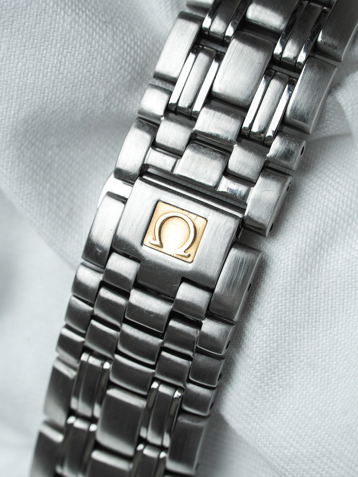 Omega vintage watch bracelet with brushed steel links and gold logo clasp