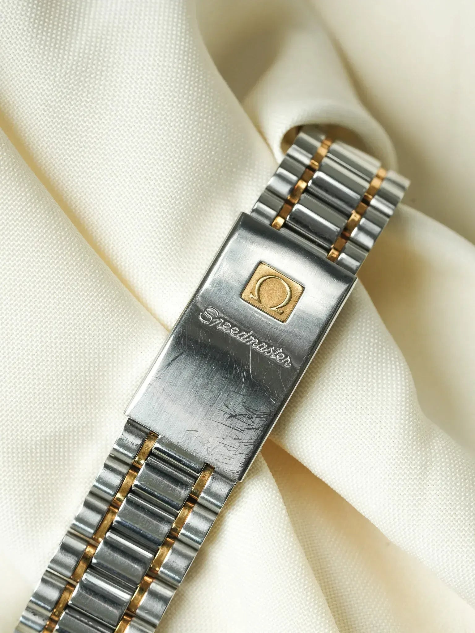 Omega Speedmaster vintage bracelet with two-tone steel and gold links on cream fabric