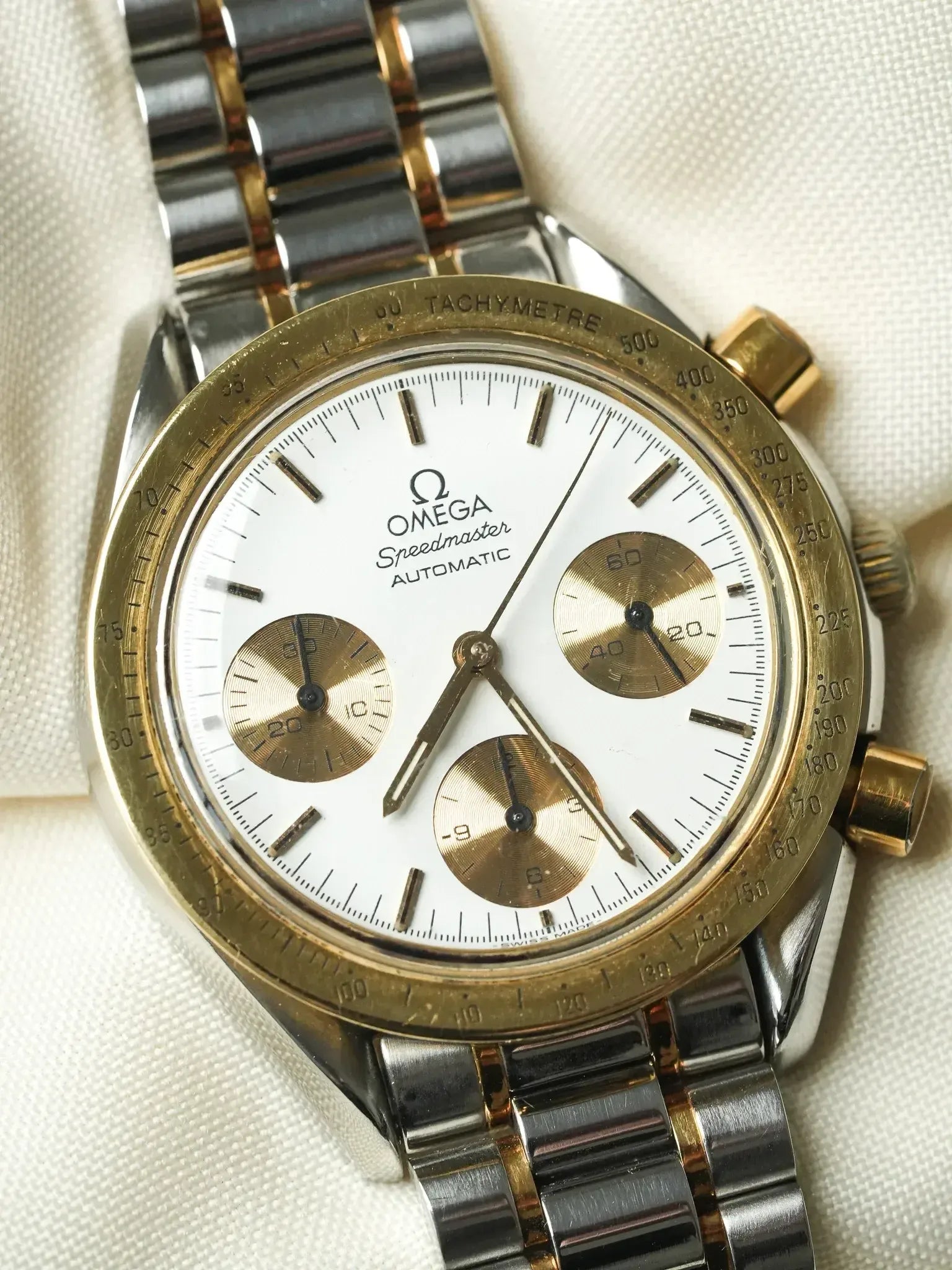 Omega Speedmaster Automatic vintage watch with white dial, gold subdials, and two-tone bracelet