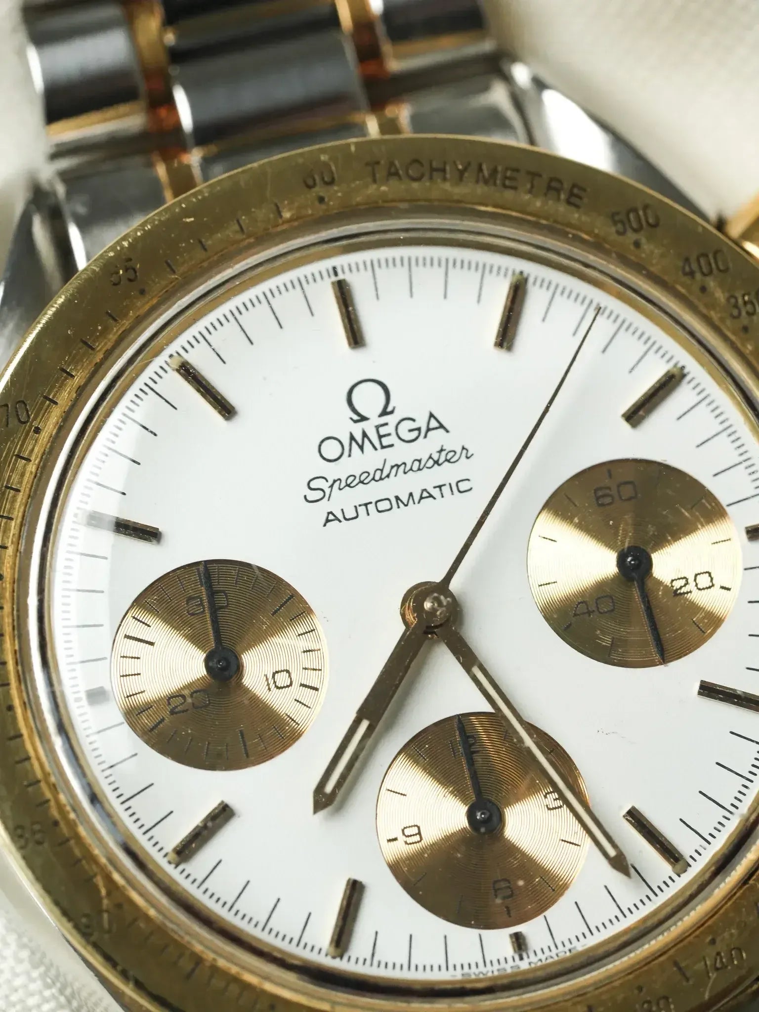 Omega Speedmaster Automatic vintage chronograph with white dial, gold subdials, and tachymeter bezel
