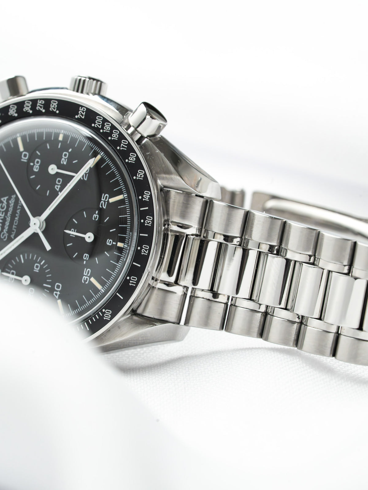 Omega Speedmaster vintage chronograph with black dial, steel case and bracelet on white background