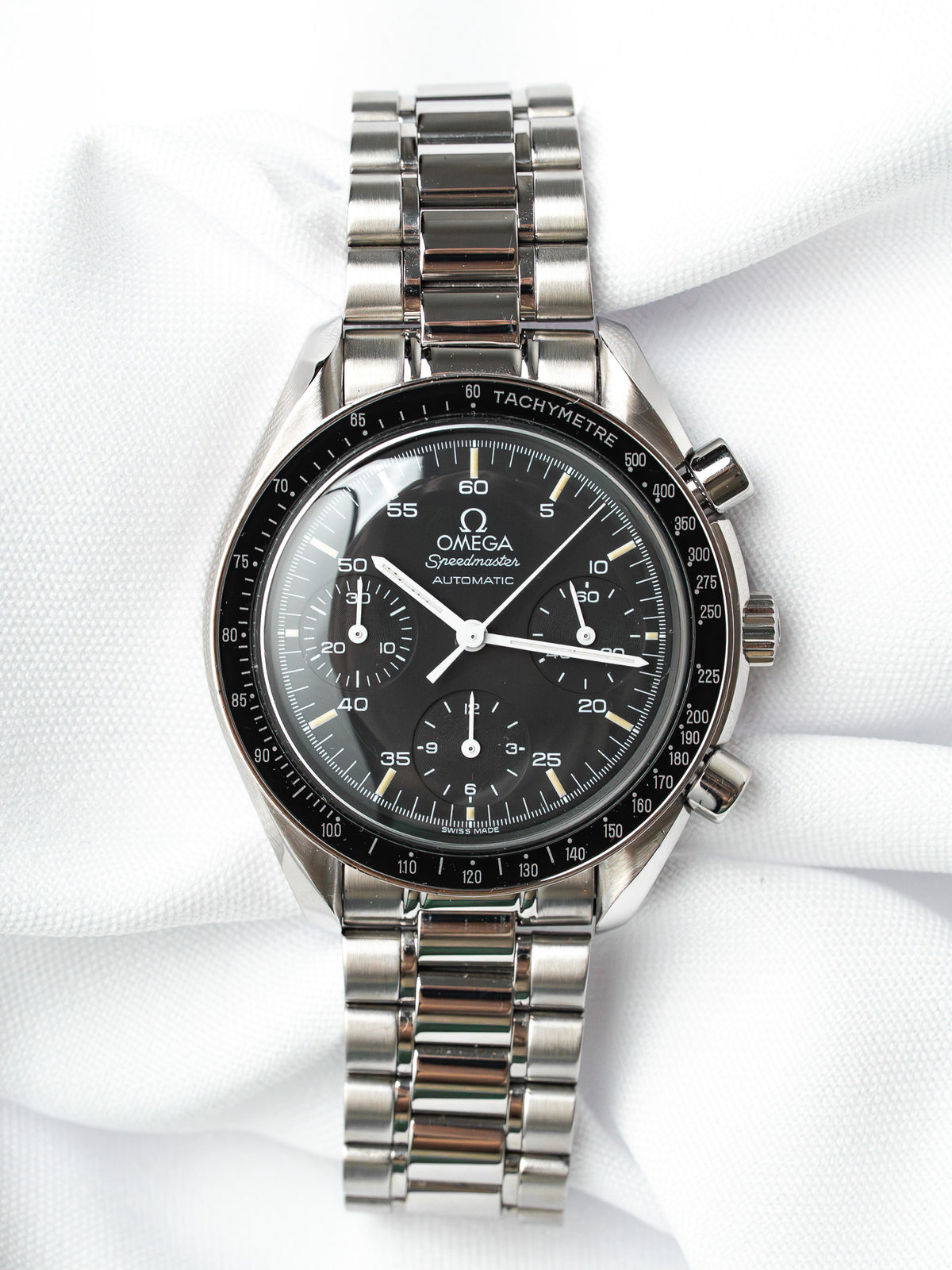 Omega Speedmaster Automatic vintage chronograph with black dial and steel bracelet on white fabric