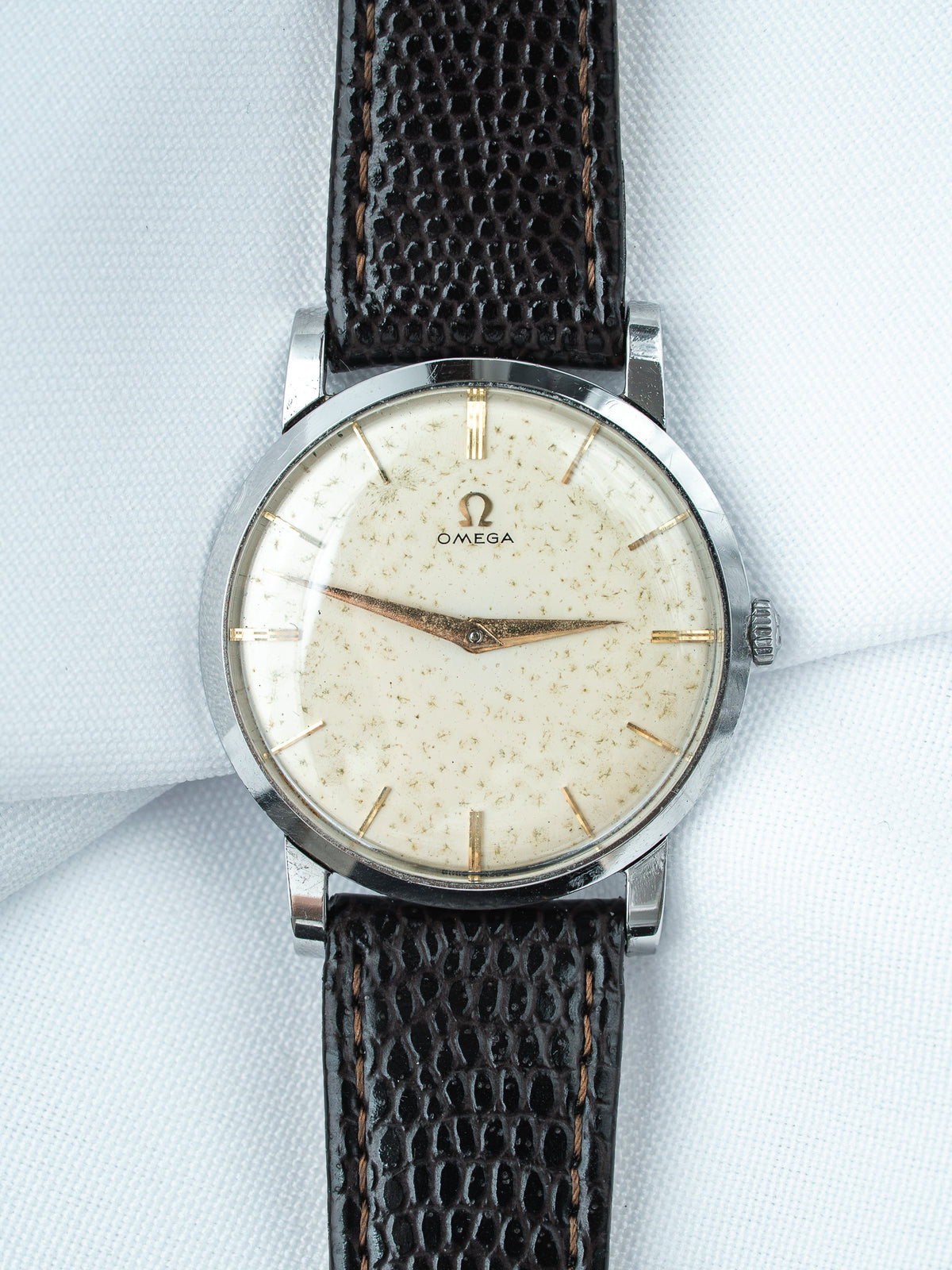 Vintage Omega watch with cream dial, gold markers, and dark textured leather strap