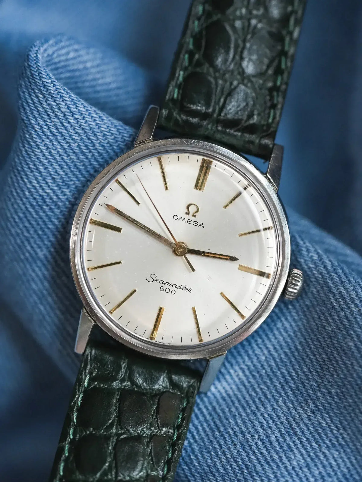 Omega Seamaster 600 vintage watch with white dial, gold markers, green alligator strap on denim