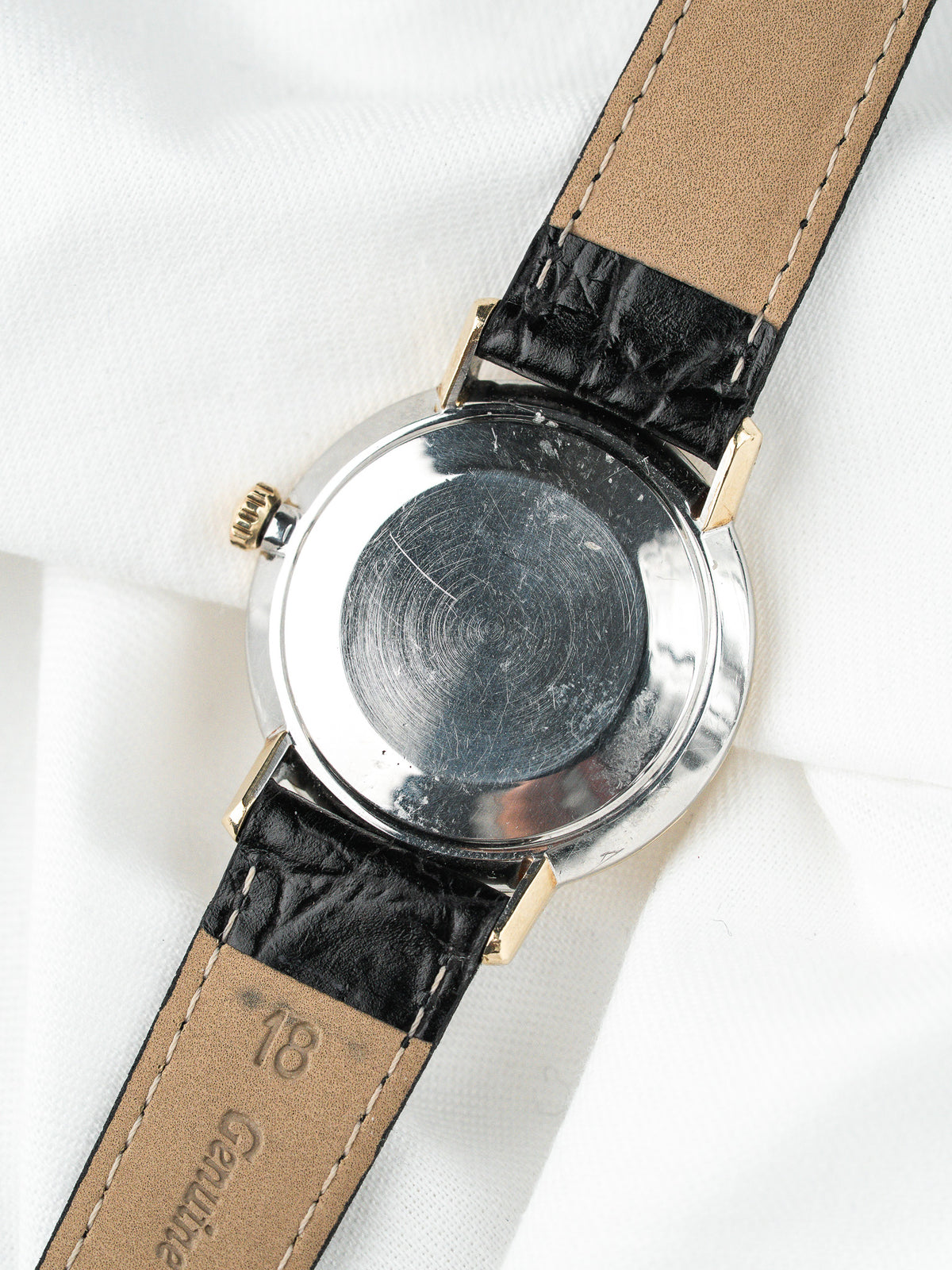 Vue arrière d'une montre vintage avec boîtier acier et bracelet en cuir noir.