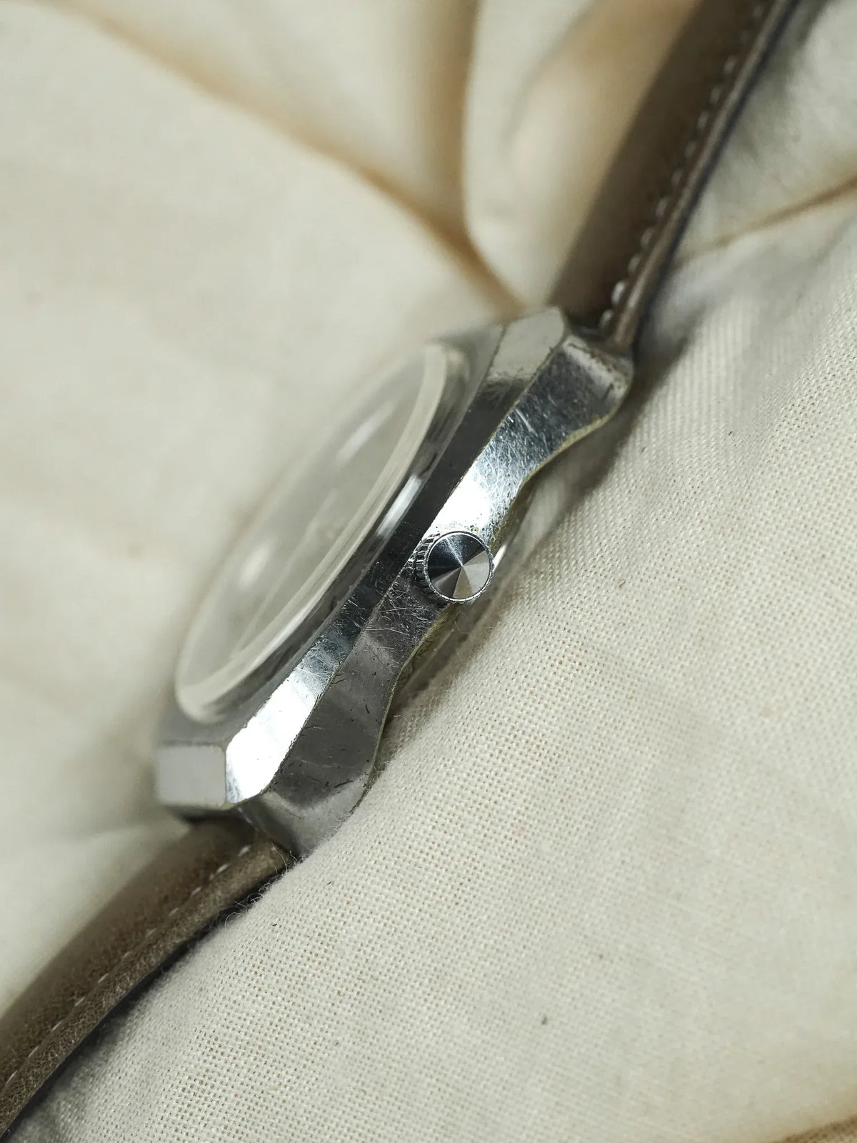 Vintage Omega watch with steel case, brown leather strap, resting on fabric