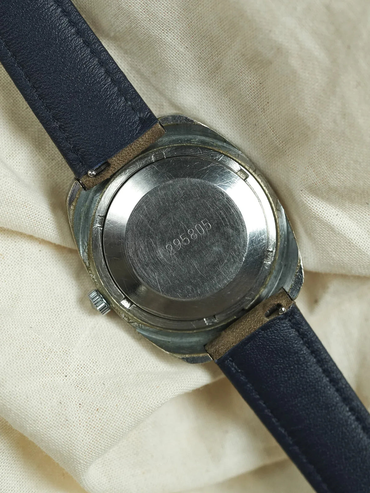 Vintage watch with steel case back engraved 295805, navy leather strap on cloth