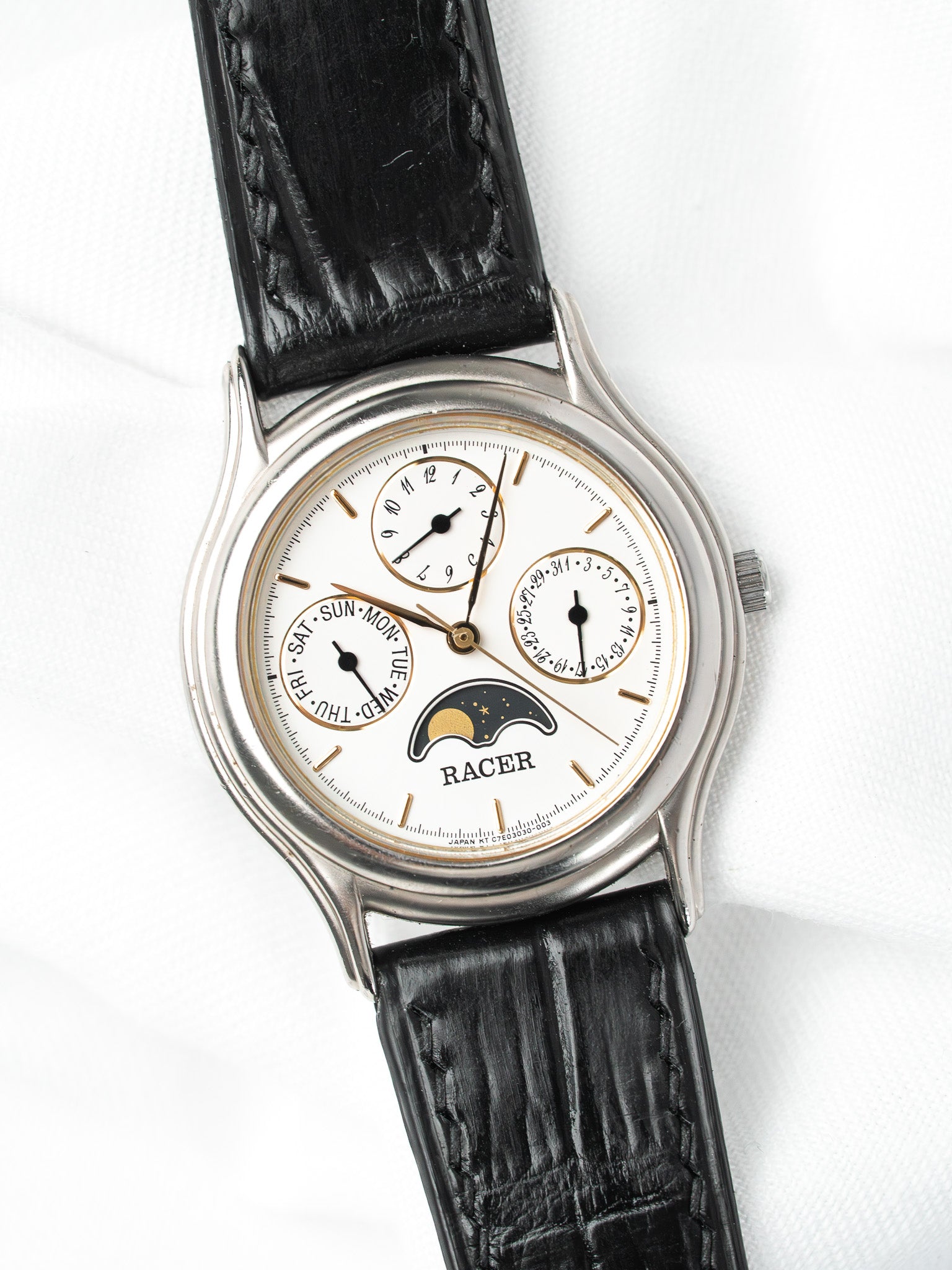 Racer vintage watch with white dial, moon phase, black leather strap on white background