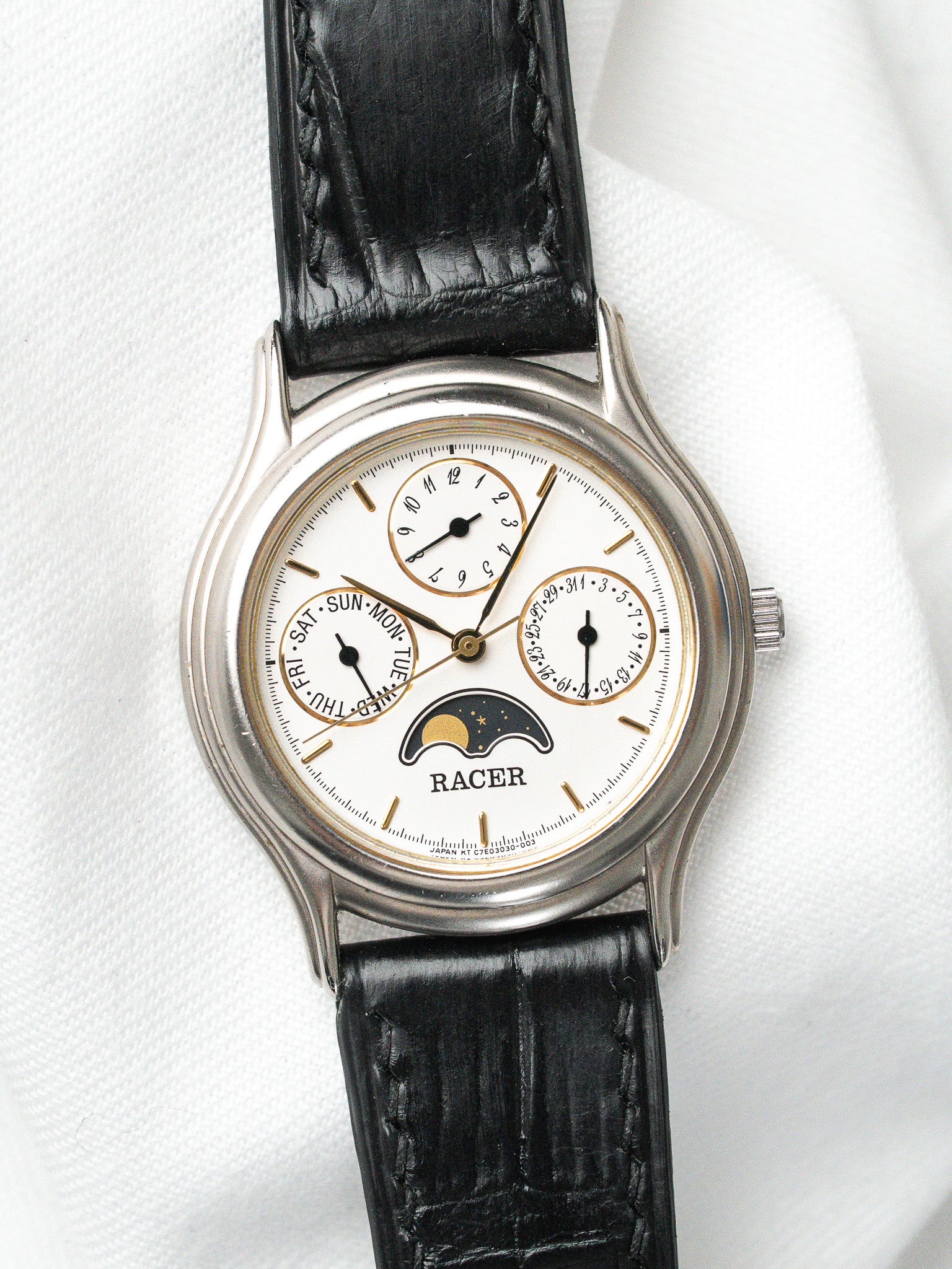 Racer vintage watch with white dial, moon phase, black leather strap on white background