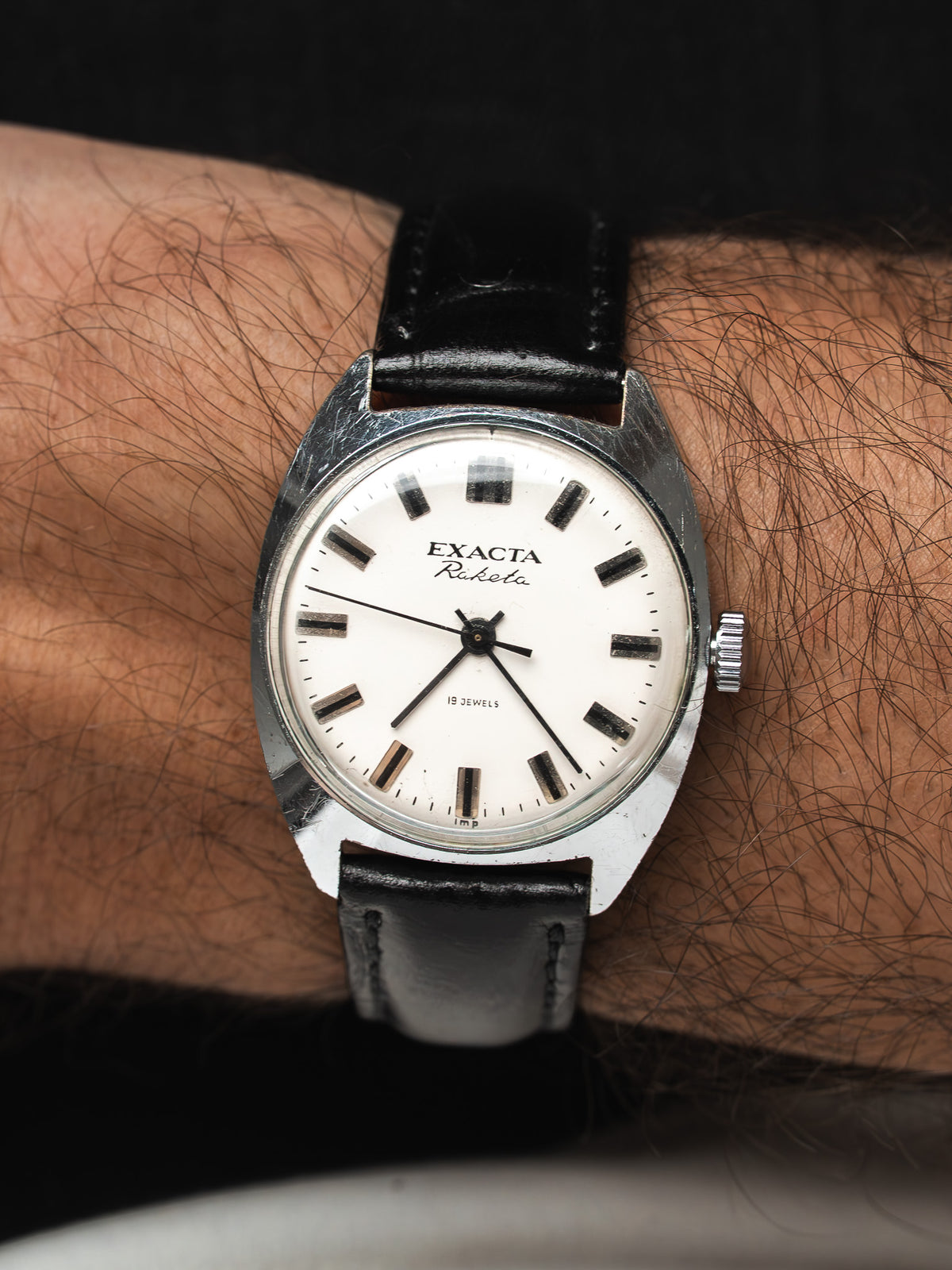 Montre vintage Exacta Raketa en acier, cadran blanc et bracelet cuir noir, au poignet