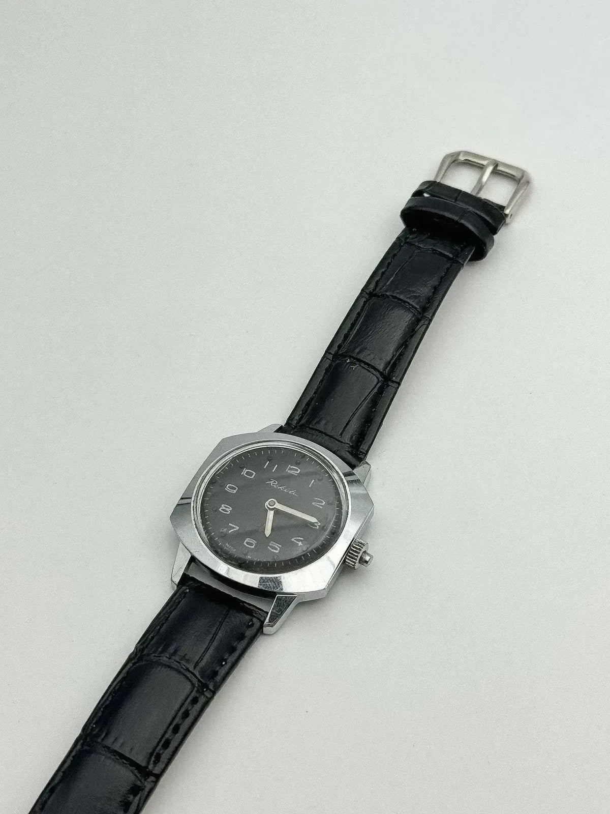 Rolex vintage watch with black dial, steel case, and black leather strap on white background