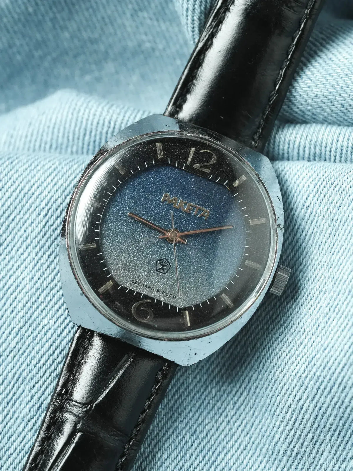 Raketa vintage watch with blue dial, black leather strap, on denim background