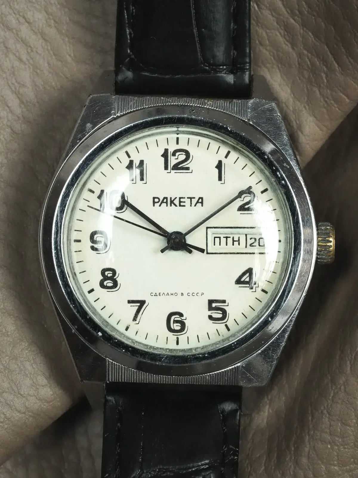 Vintage Raketa watch with white dial, black leather strap, and Soviet-era Cyrillic text