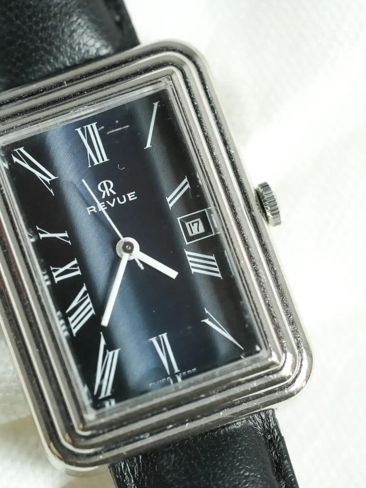 Revue vintage watch with black dial, Roman numerals, and black leather strap