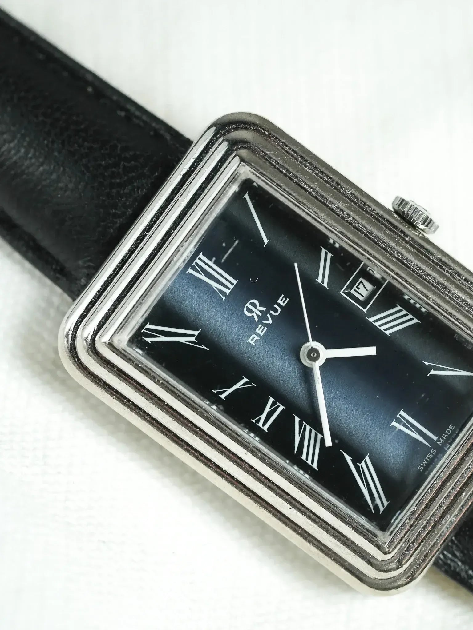 Revue vintage watch with black dial, Roman numerals, steel case, and black leather strap