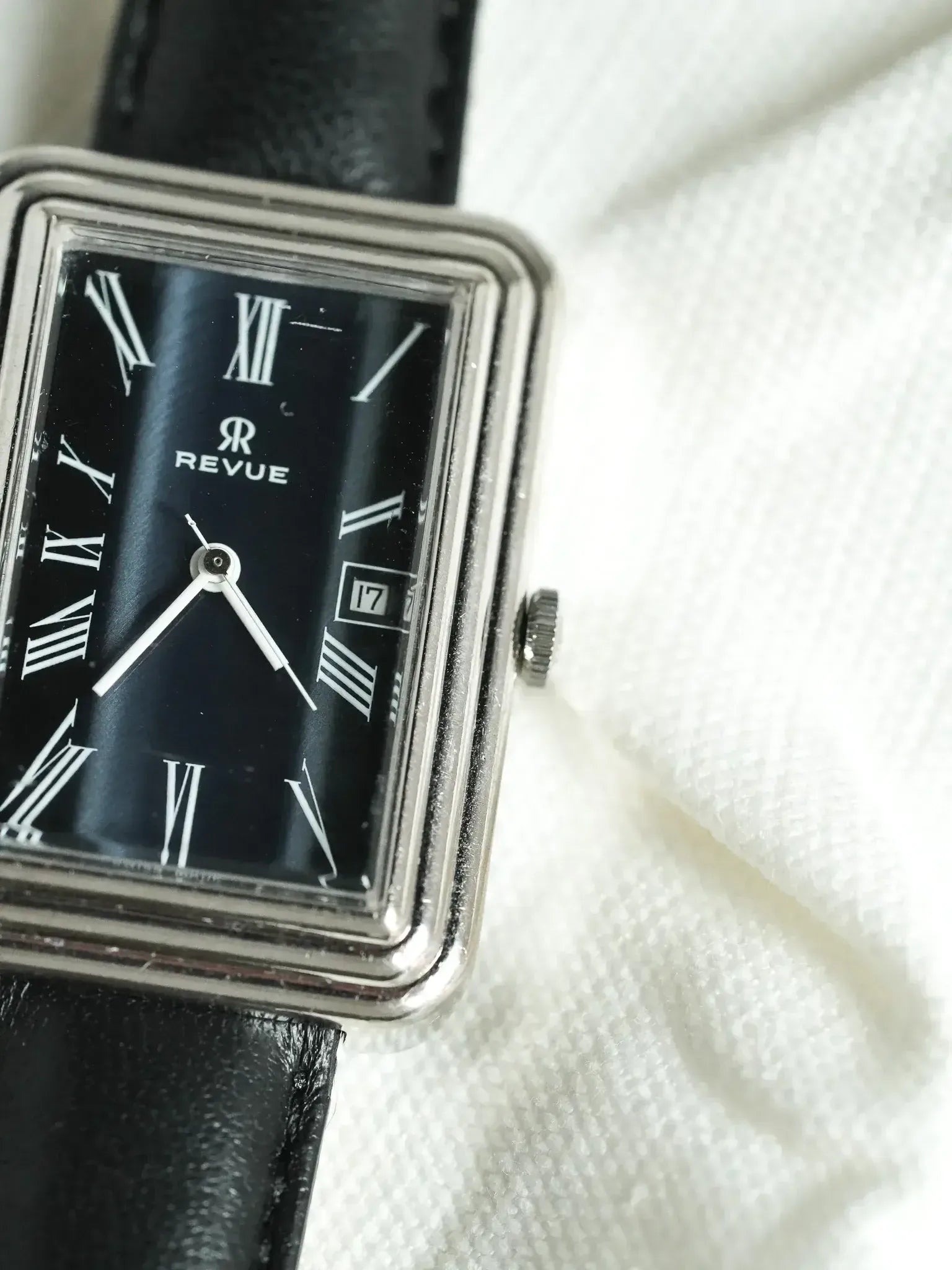 Revue vintage watch with black dial, Roman numerals, and black leather strap