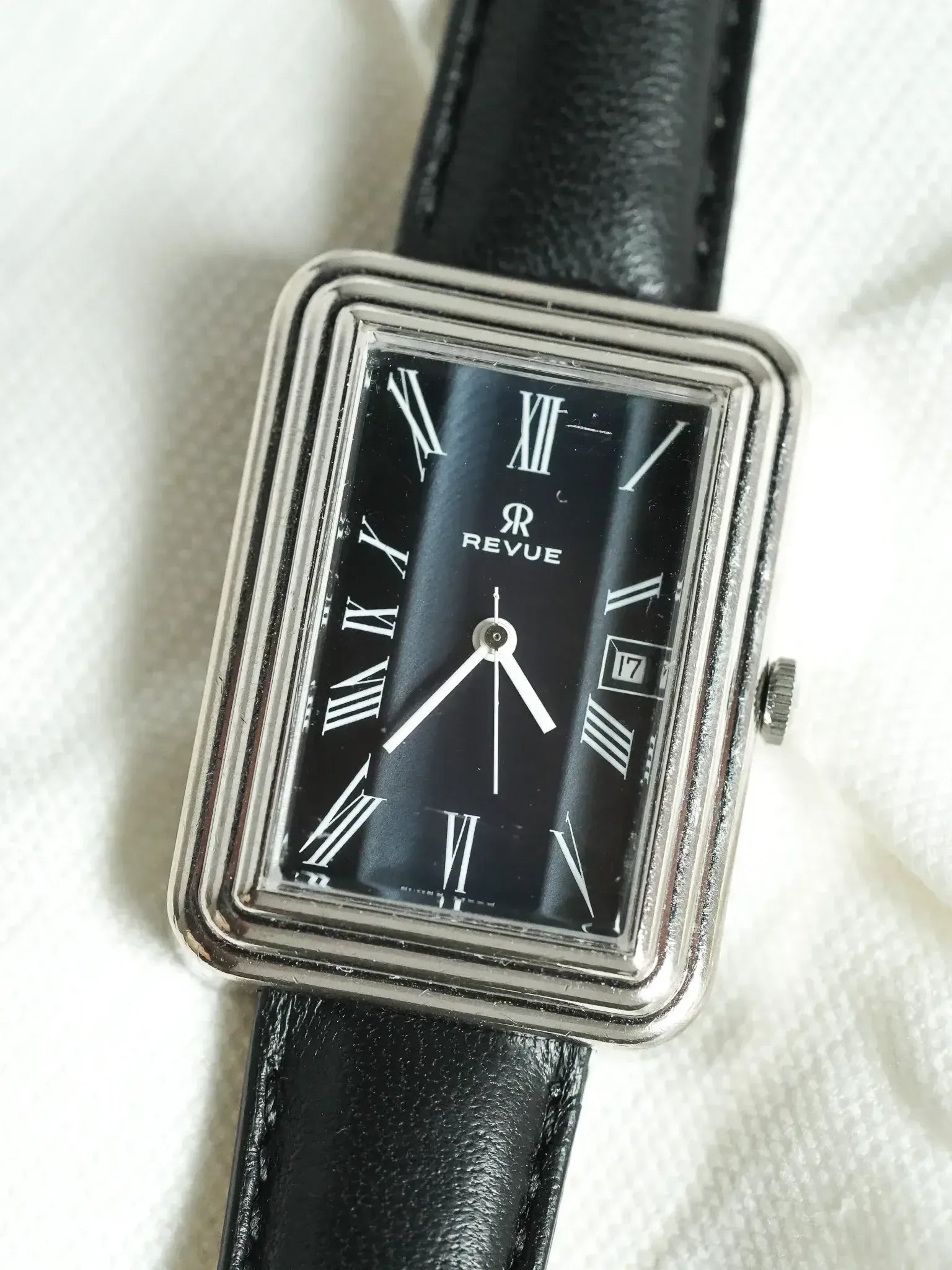 Revue vintage watch with black dial, Roman numerals, and black leather strap