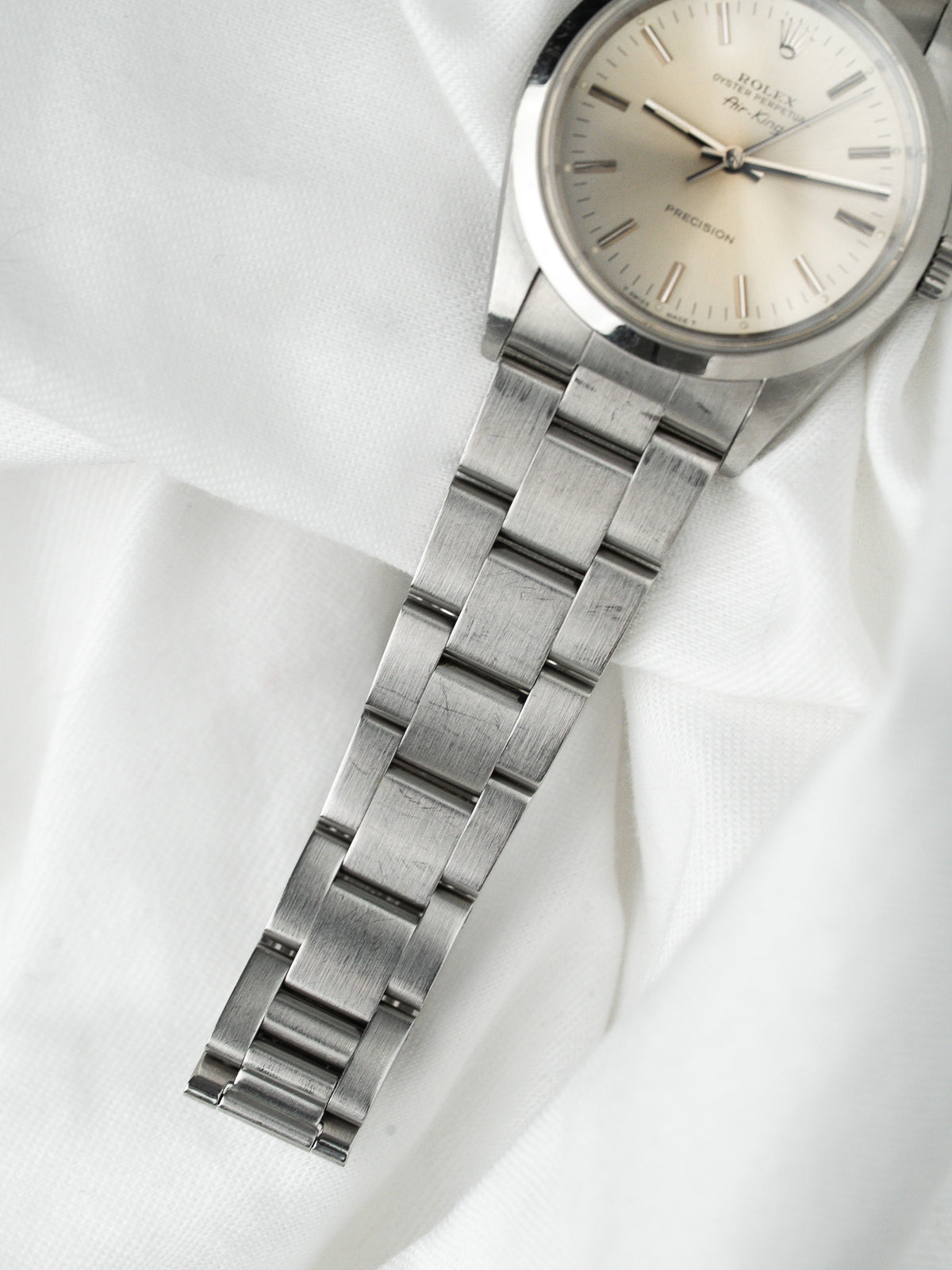 Montre Rolex Air King vintage en acier, cadran argenté, posée sur tissu blanc