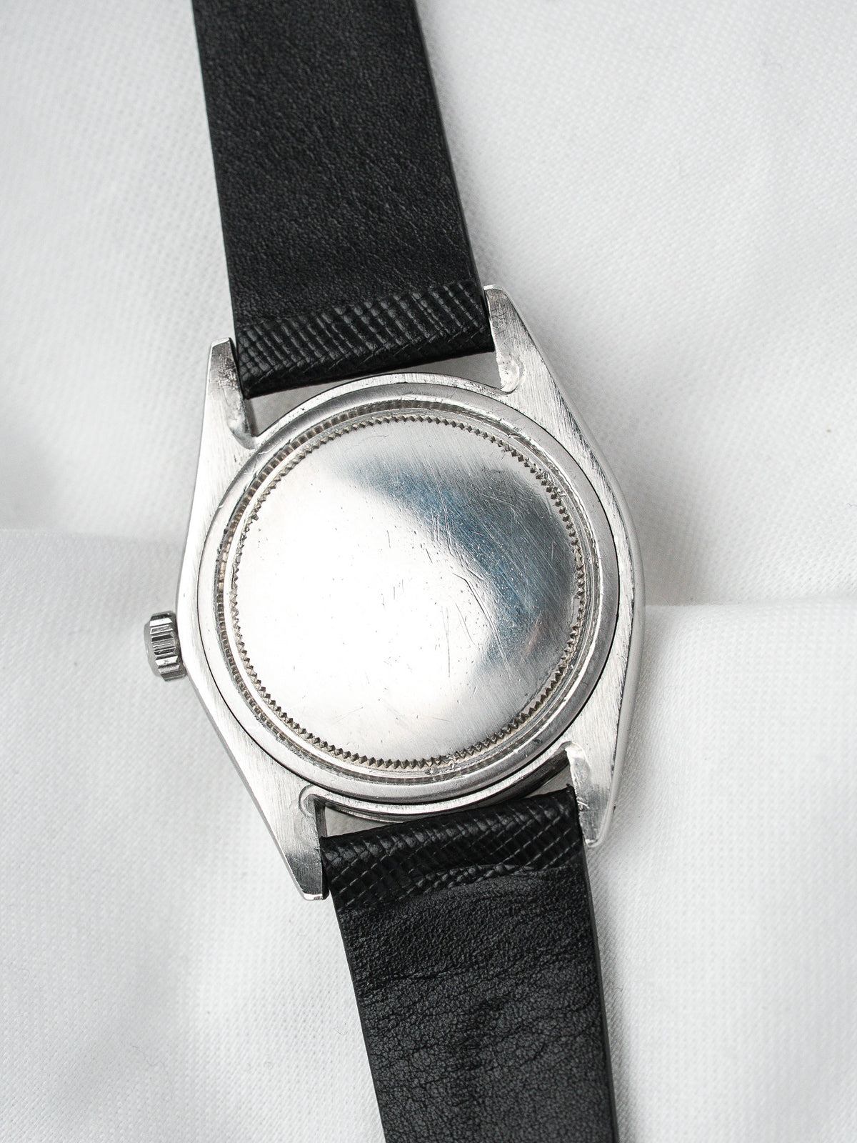 Vintage watch with steel case and black leather strap, back view
