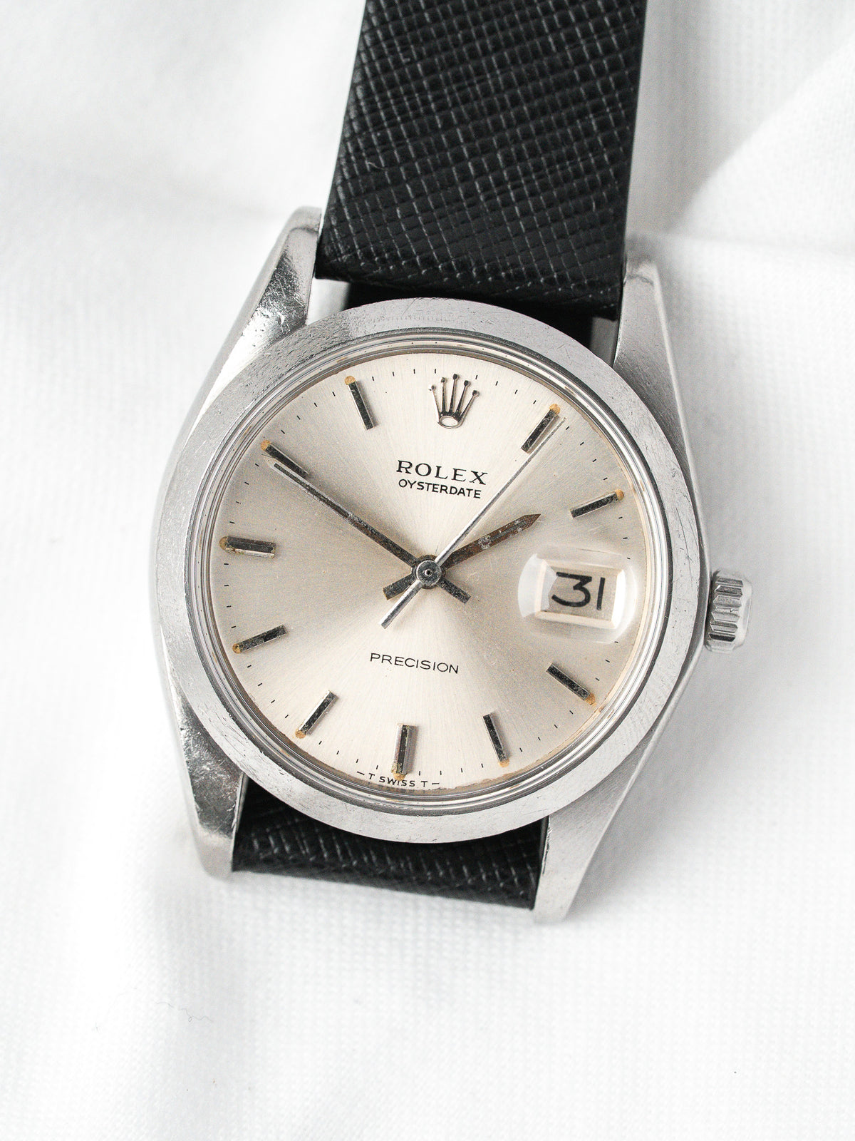 Rolex Oysterdate vintage watch with silver dial, black strap, and date display