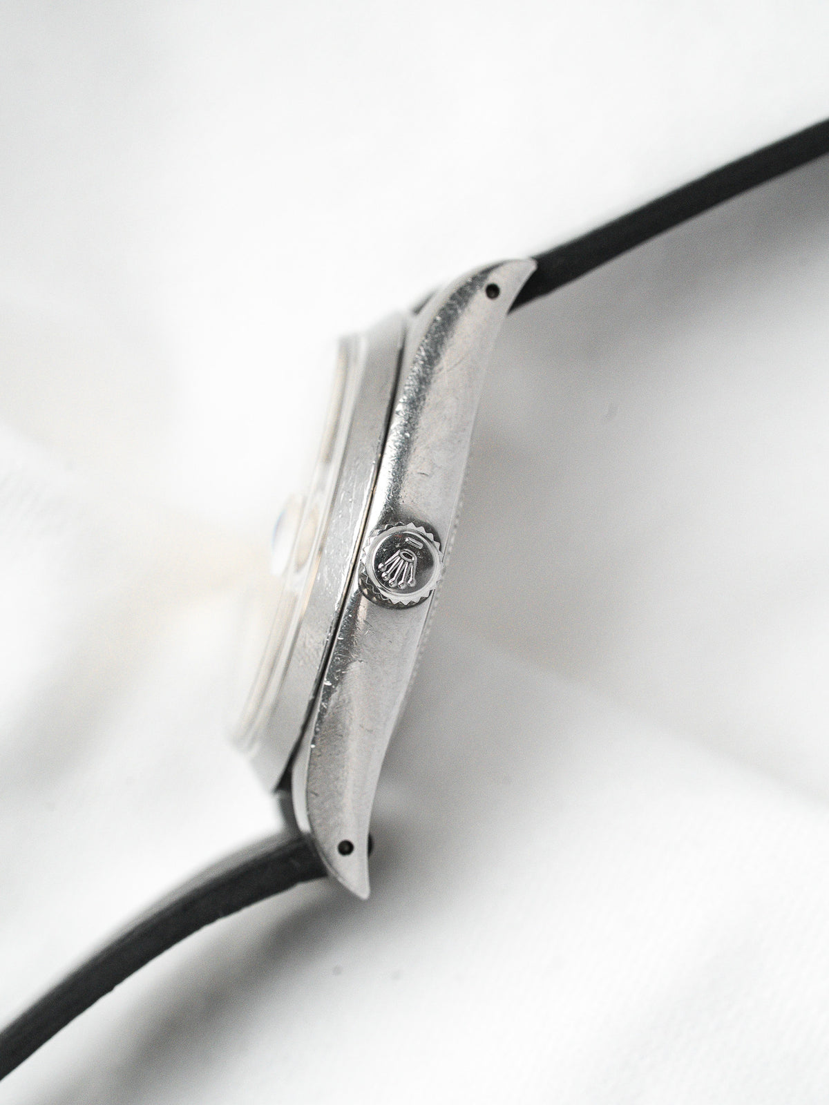 Rolex vintage watch with steel case and black strap, side view