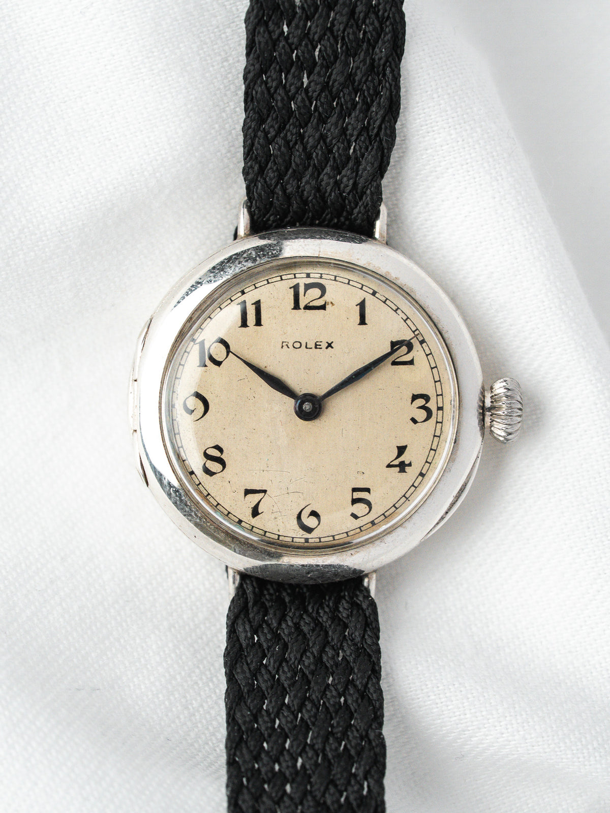 Montre Rolex vintage, boîtier rond argenté, cadran crème et bracelet textile noir