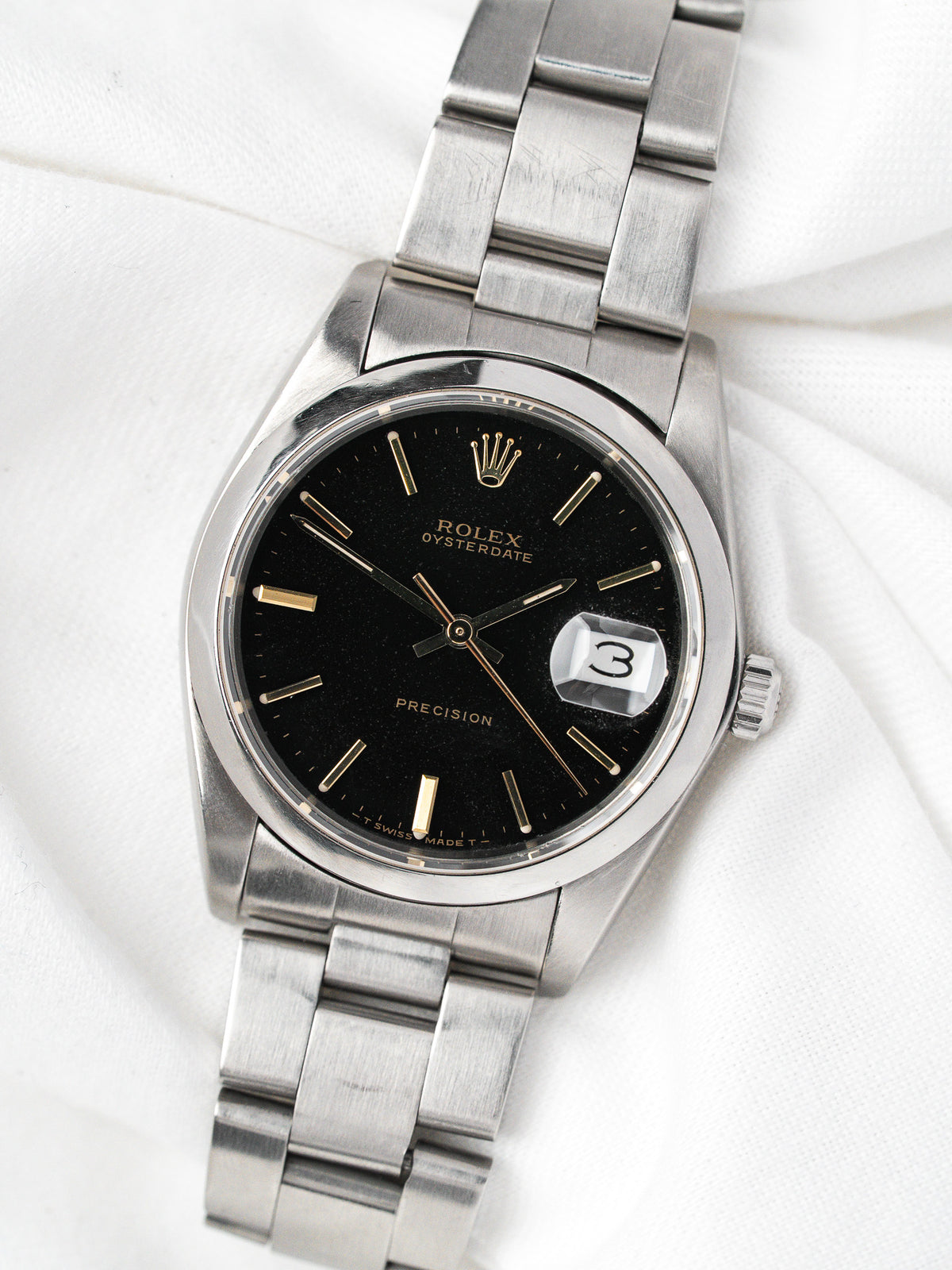 Montre Rolex Oysterdate vintage en acier, cadran noir et bracelet métallique, sur fond blanc