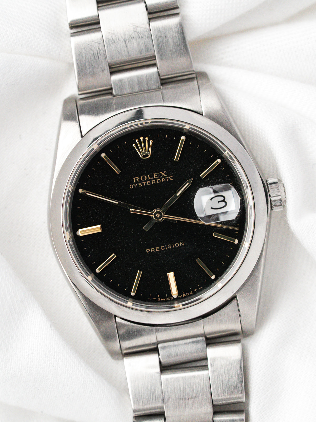 Montre Rolex Oysterdate vintage en acier, cadran noir avec index or, fond blanc