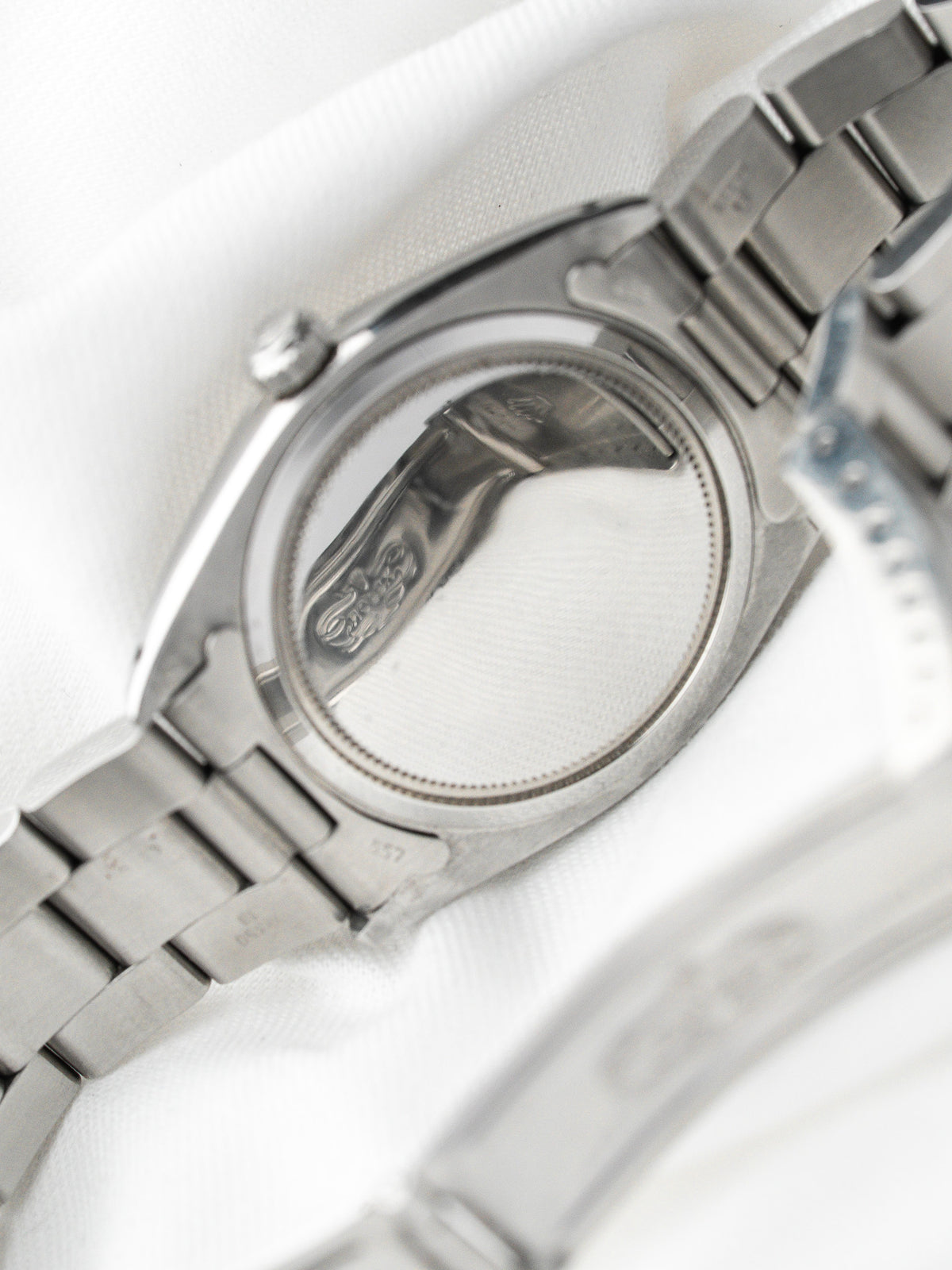 Dos d'une montre vintage en acier avec bracelet métallique sur fond blanc
