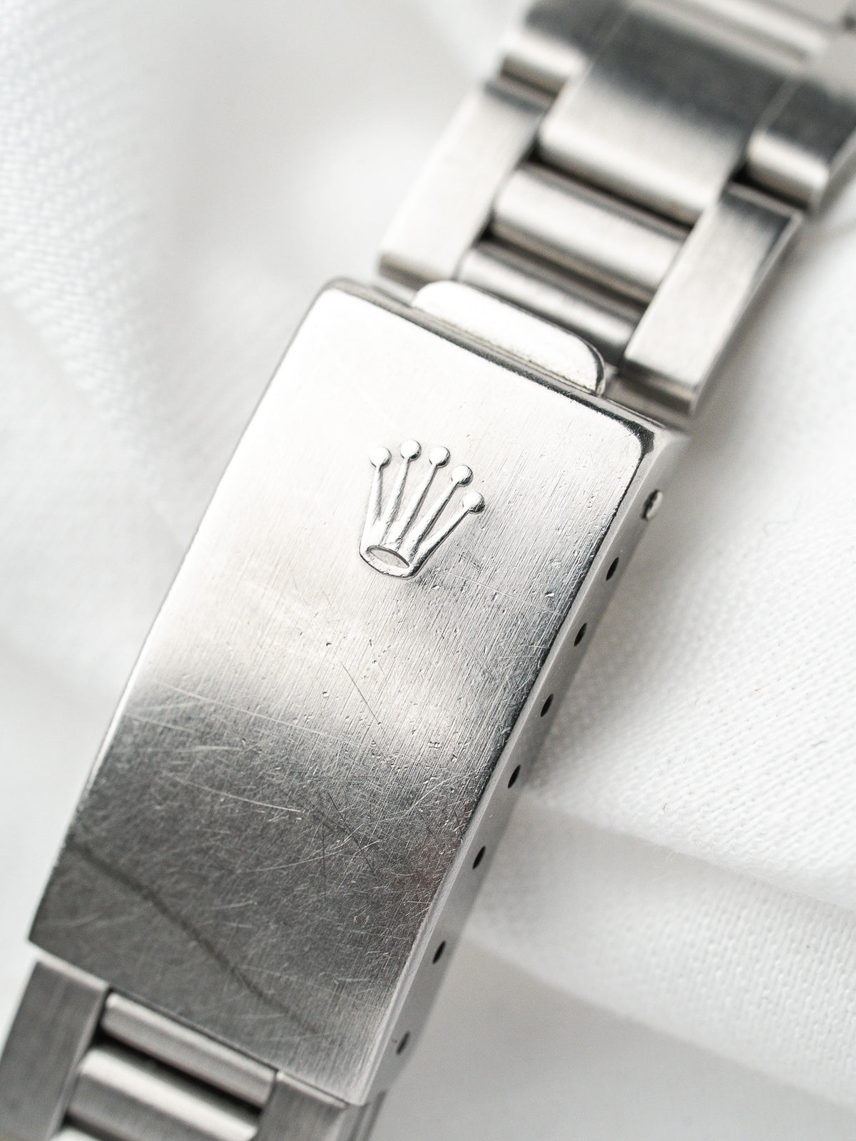 Fermoir de montre Rolex en acier avec logo couronne gravé sur fond blanc